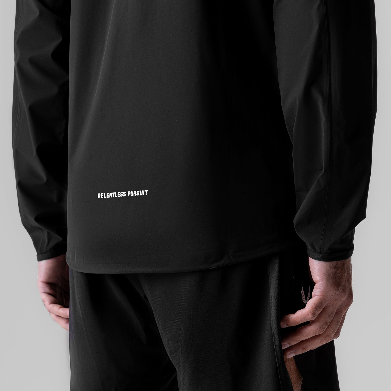 Black Aerotex Lightweight Windbreaker worn by model, back view showing 'Relentless Pursuit' text