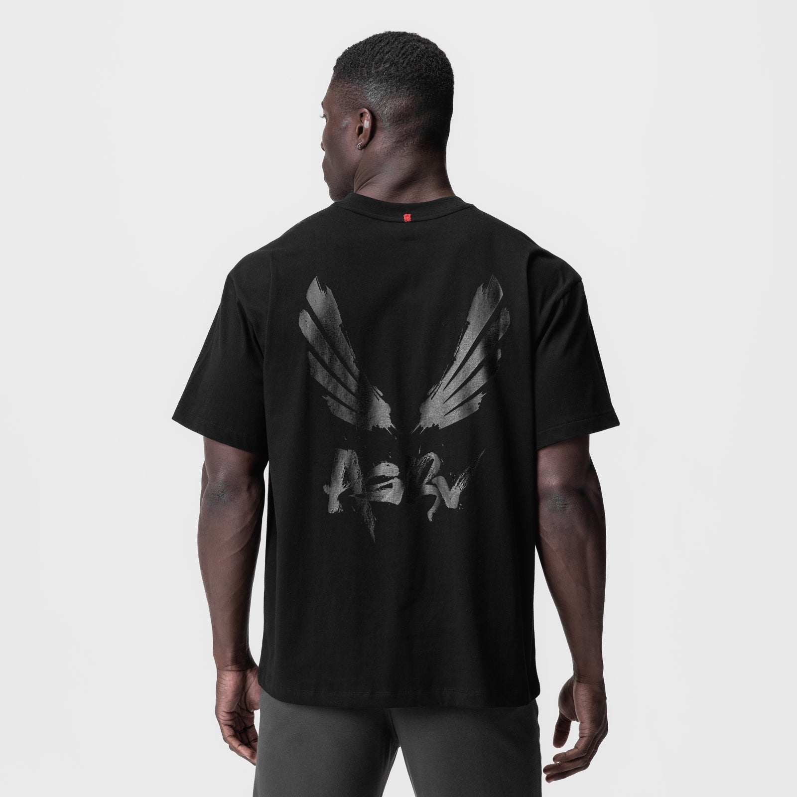 Black Tech Essential Relaxed Tee with brush wings graphic, back view on model