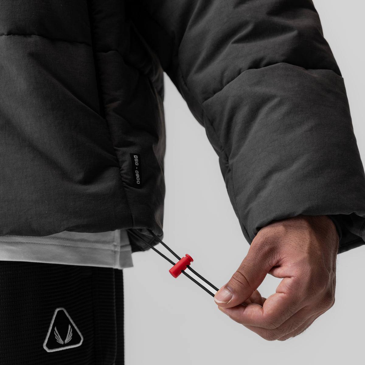 Black PrimaLoft® puffer jacket worn by model, showing drawstring detail and side view