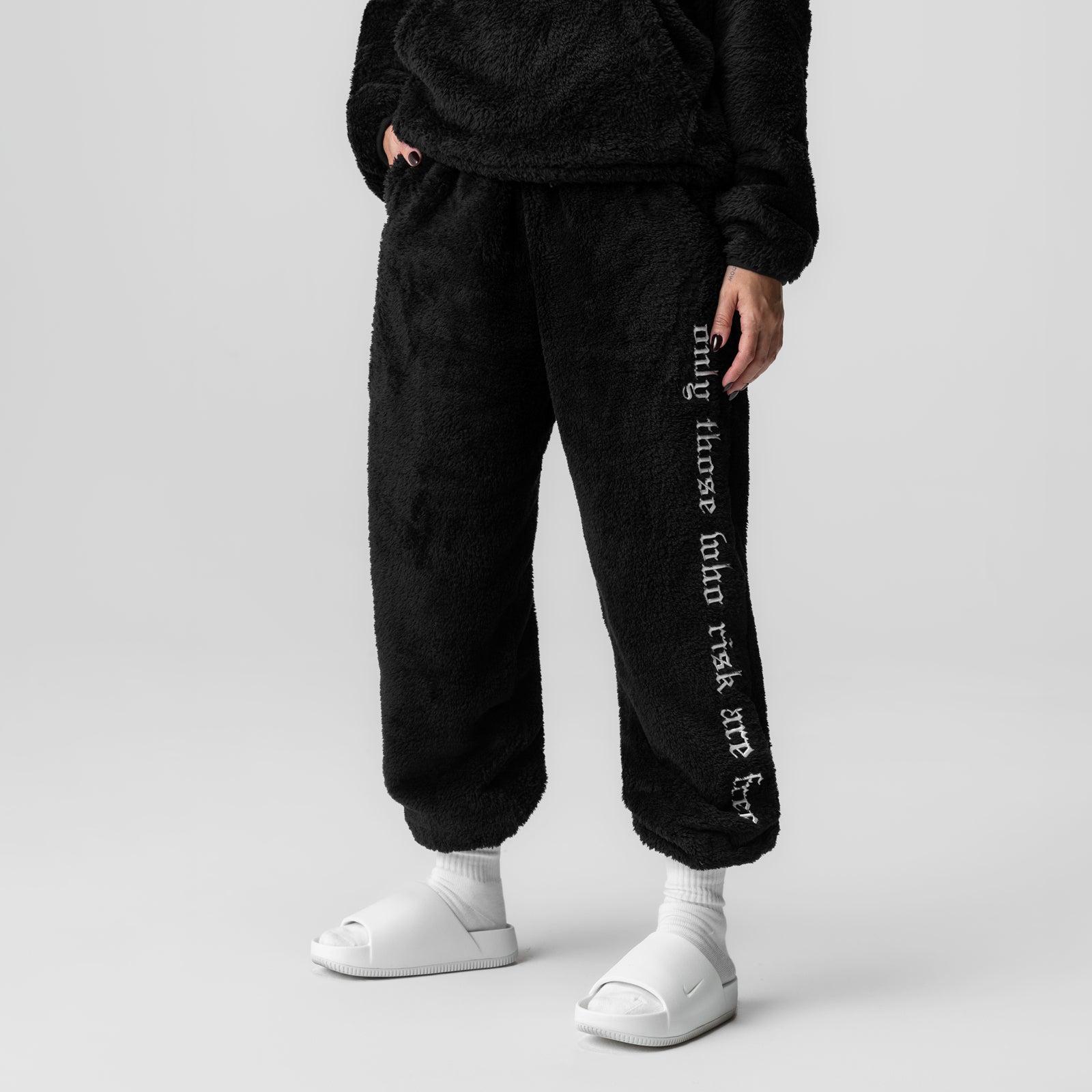 Black sherpa recovery sweats on model with white socks and sneakers, side view