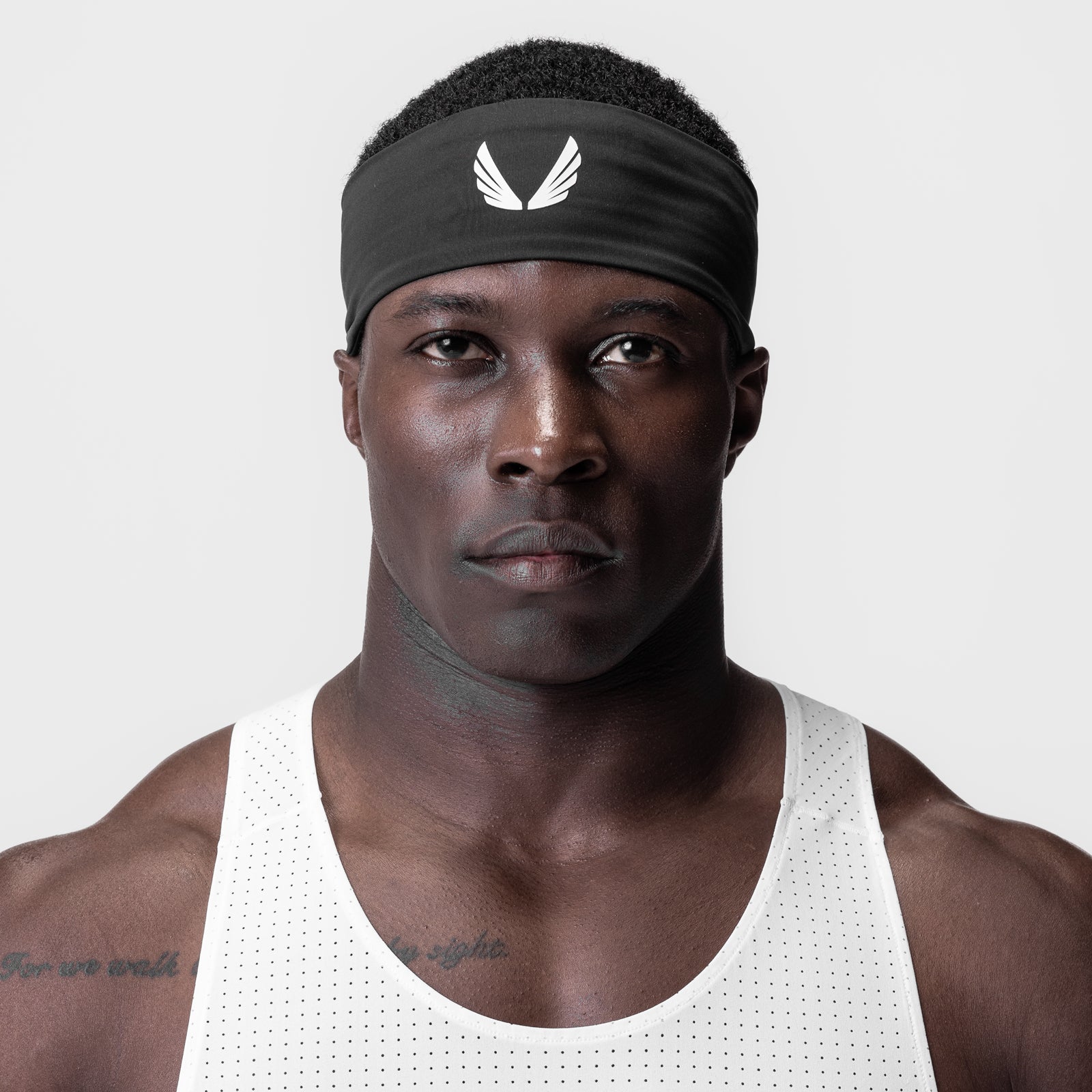 WarpFlexx Headband in black with white wings logo, worn by male athlete in white tank top
