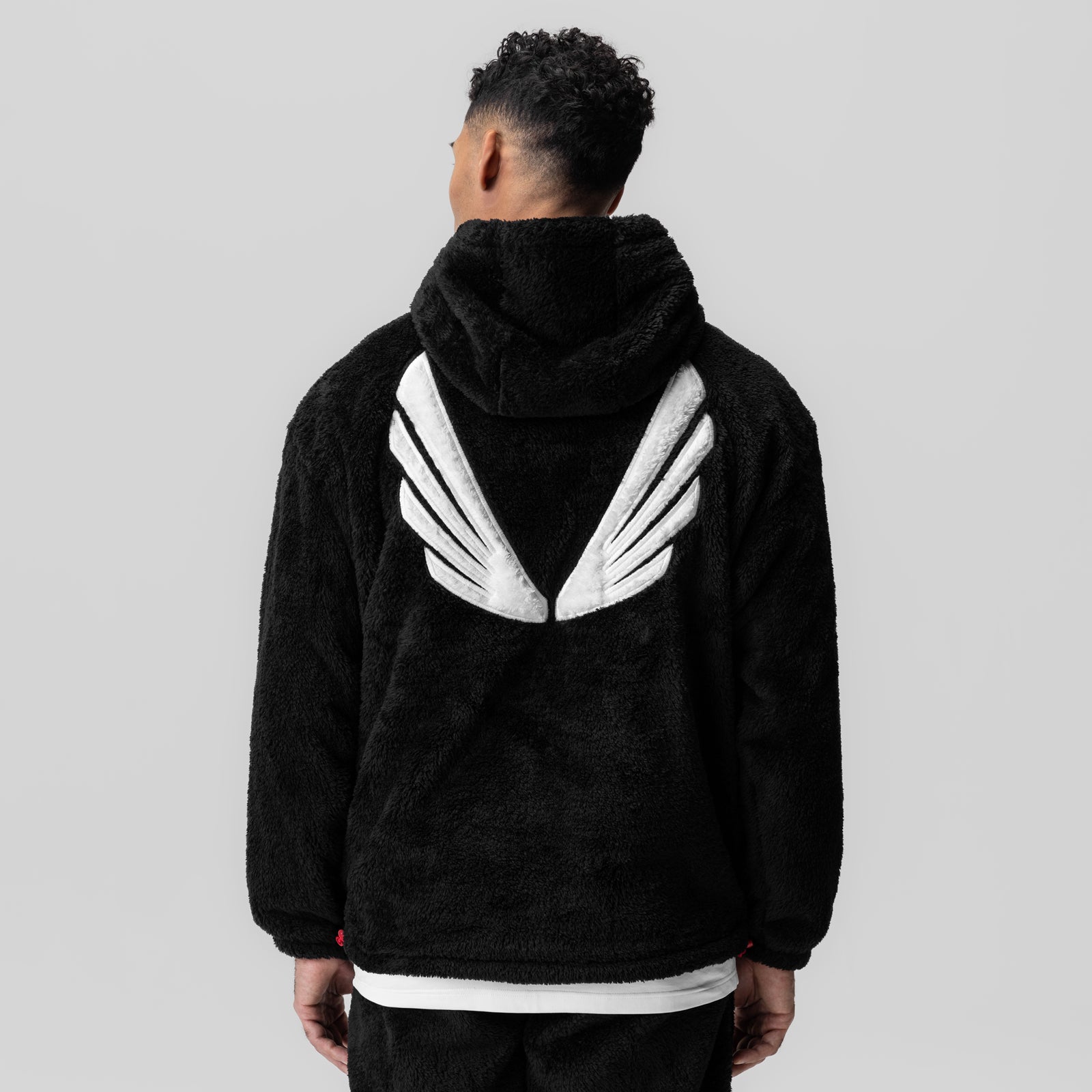 Black Sherpa Recovery Hoodie with white wings design on back, worn by model, rear view