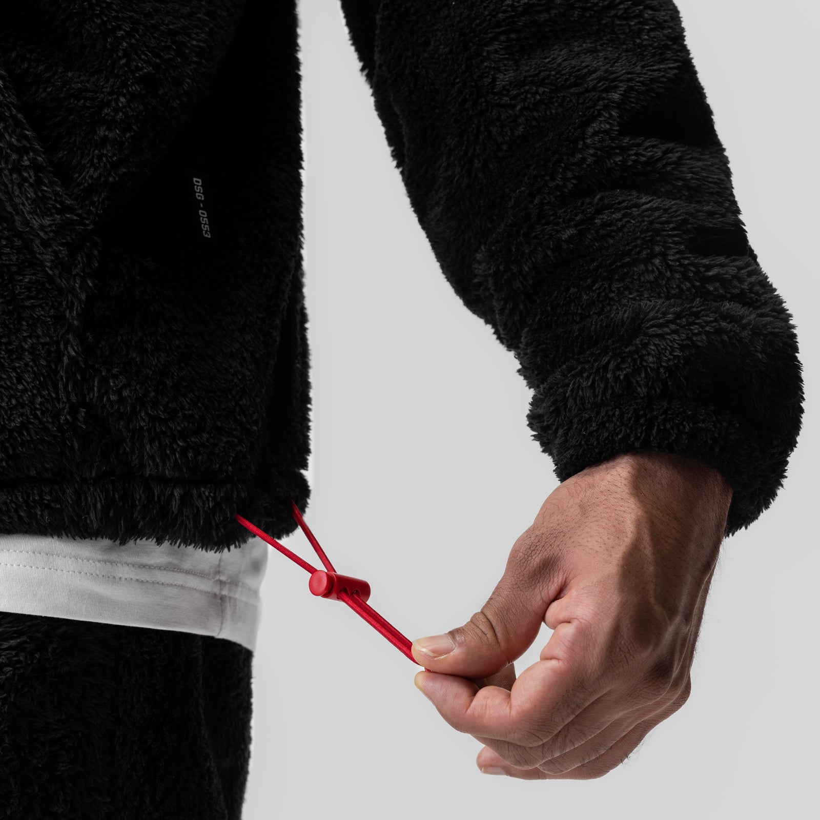 Model wearing black Sherpa Recovery Hoodie with red drawstring detail, hand closeup view