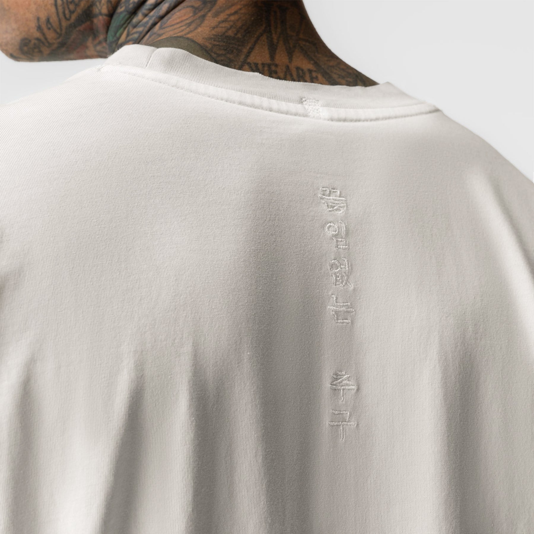 Tech Essential Relaxed Long Sleeve in Faded Stone, back view on model showing vertical text detail