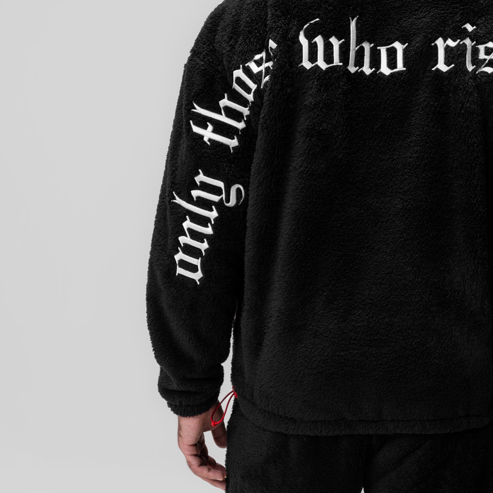 Black Sherpa Recovery Hoodie worn by model, showing sleeve text detail and red cuff accent