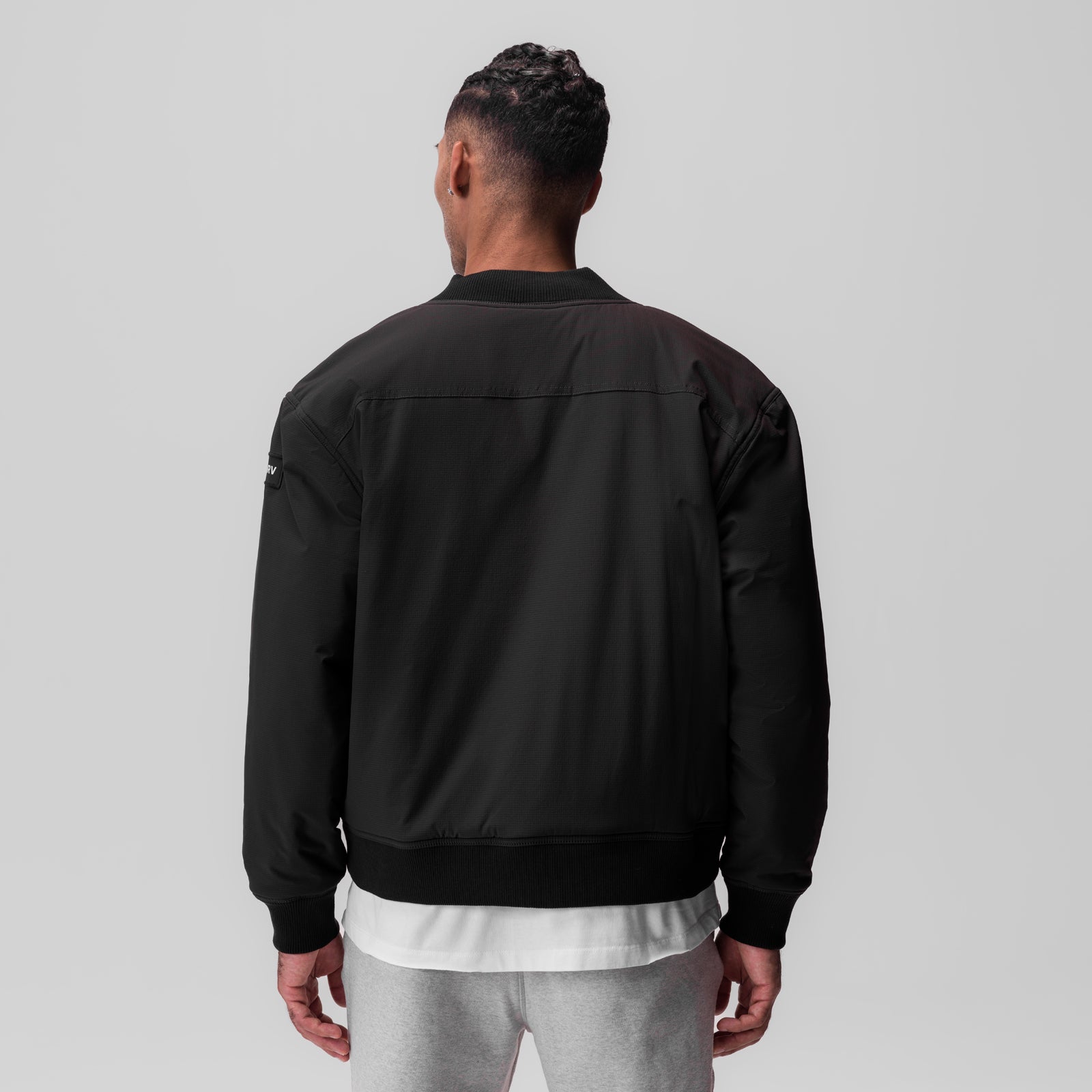 Black ripstop insulated bomber jacket worn by model, back view