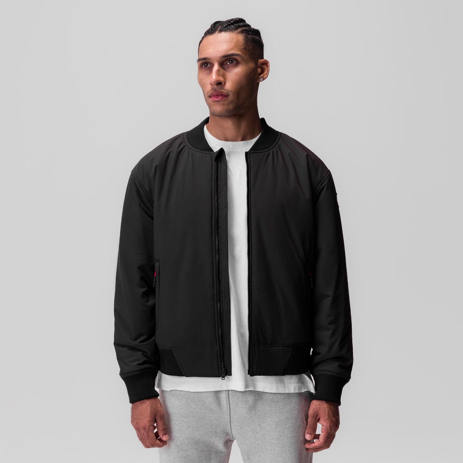 Black ripstop insulated bomber jacket worn with white tee and grey joggers, front view