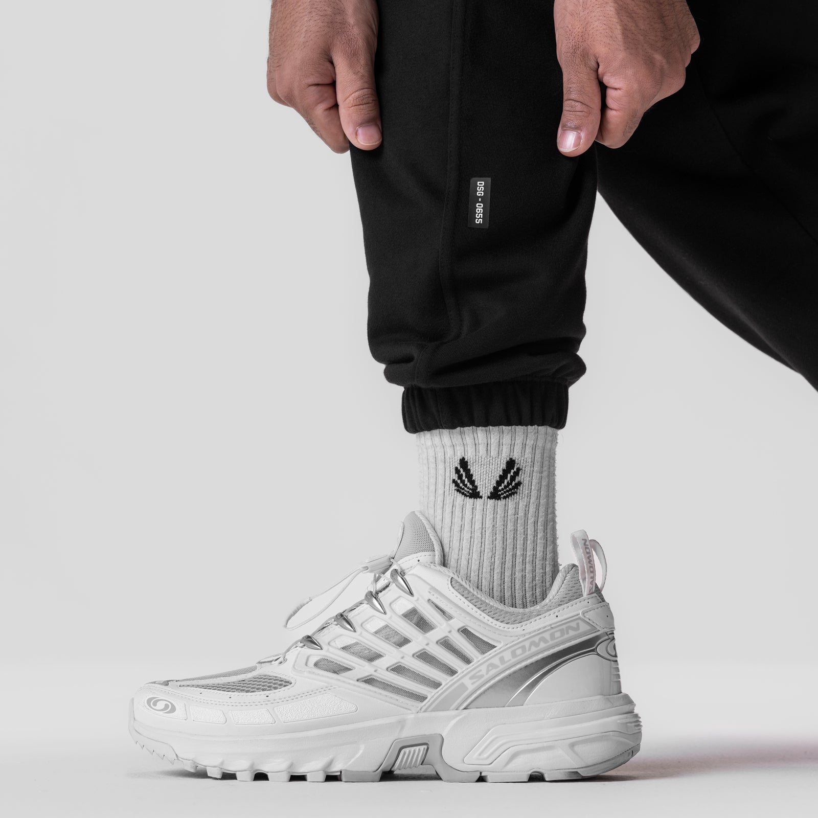 Black Tech-Terry oversized sweats on model wearing white sneakers and white socks, calf detail view