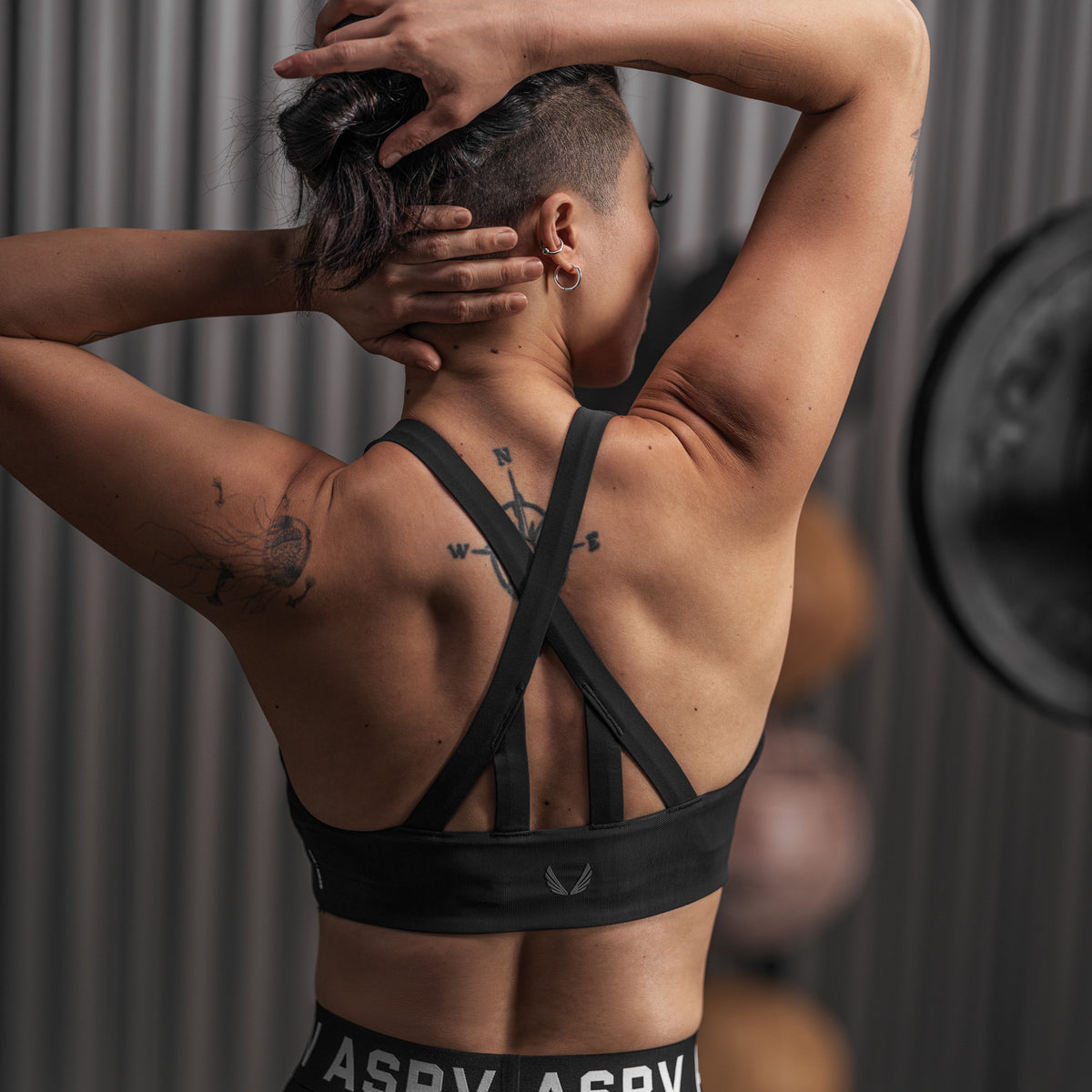 Black LYCRA® Hybrid Sports Bra worn by model with hands behind head, back view