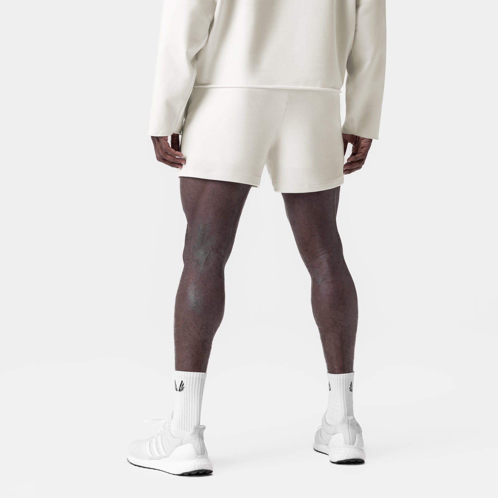 Waffle knit sweat shorts in cream worn with white socks and sneakers, back view