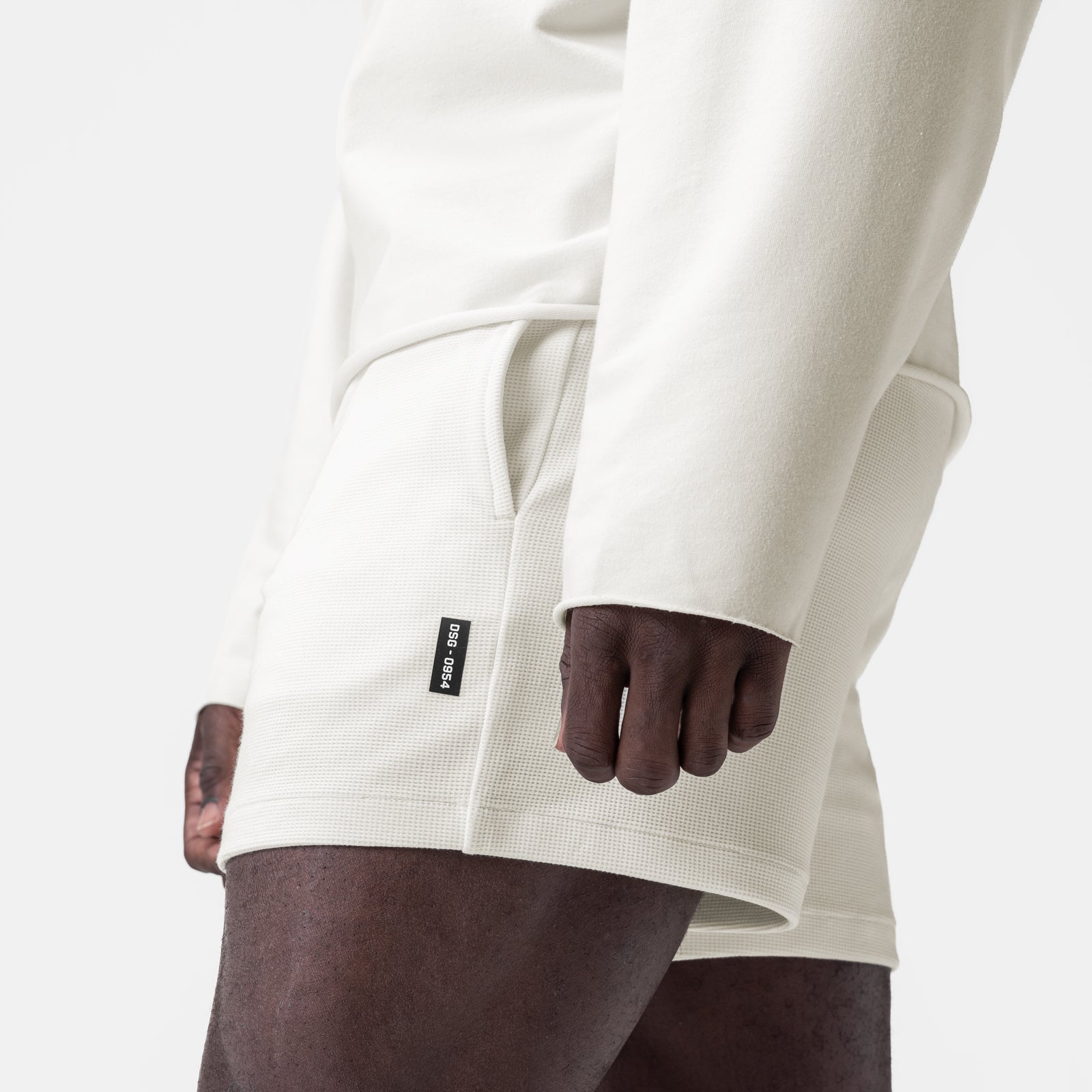 Waffle knit sweat short in cream, worn by model with brown shorts, side view