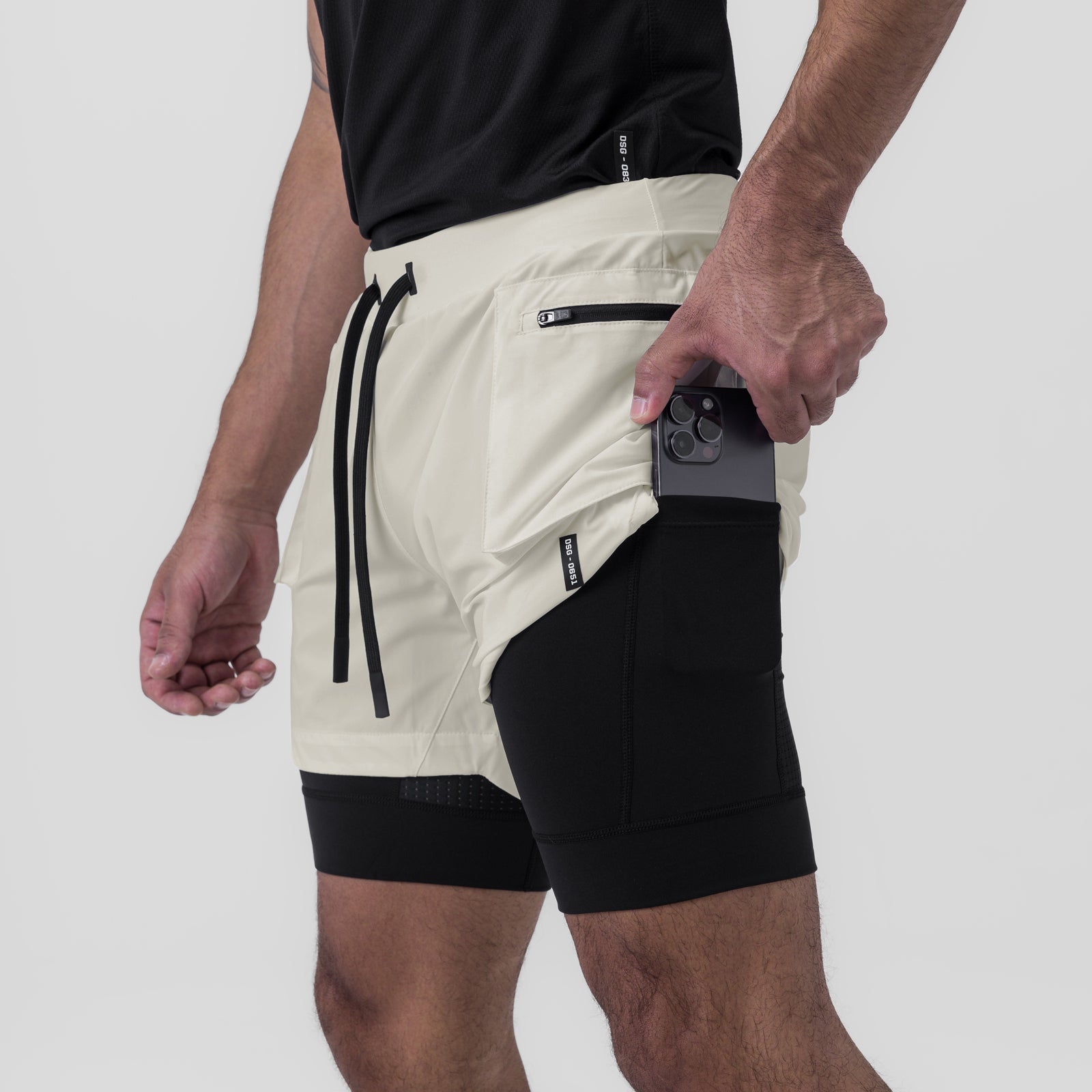Tetra-Lite Cargo Short in stone and black, worn by model holding phone in side pocket