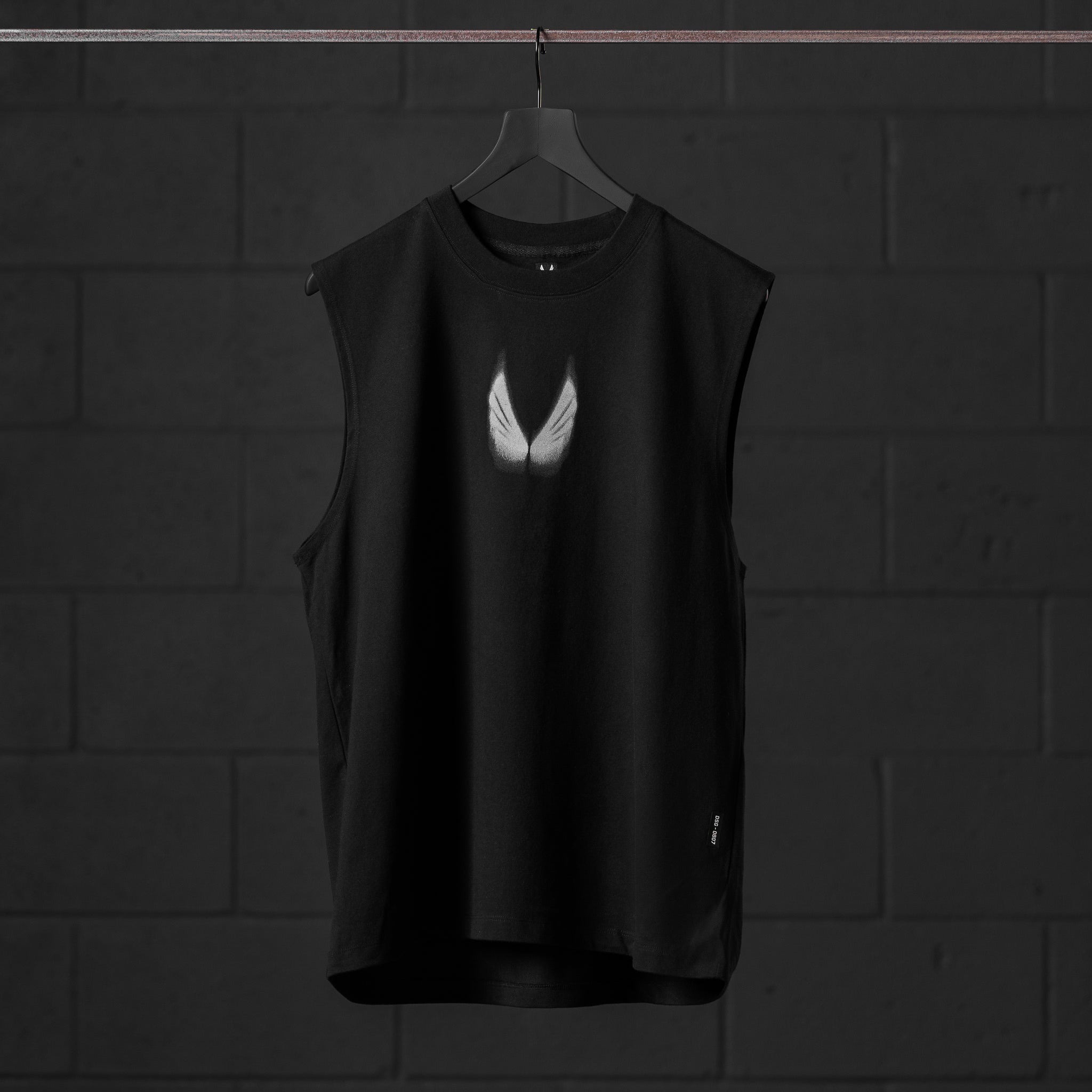 Black Tech Essential Relaxed Cutoff tank top with white wing graphic, displayed on hanger