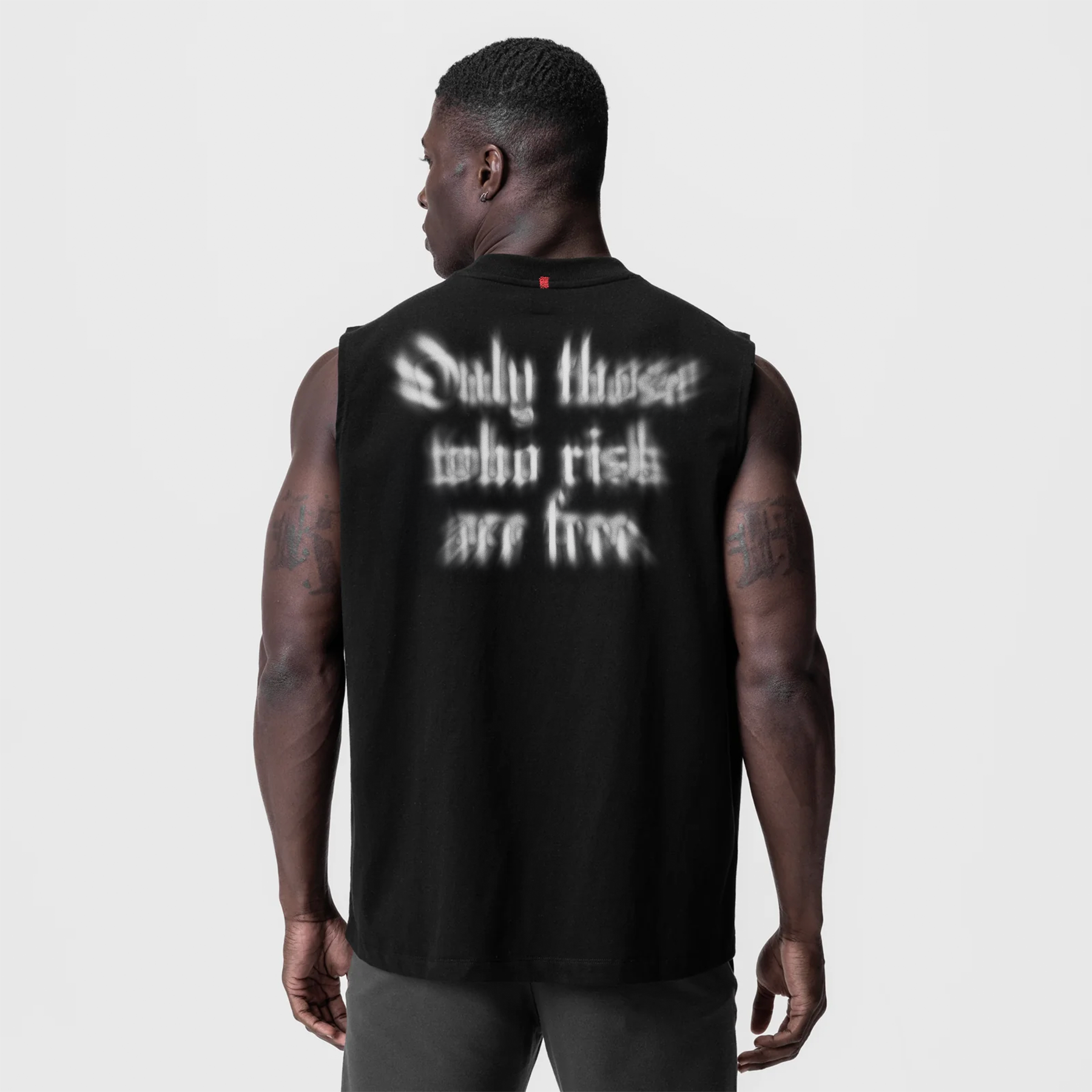 Black Tech Essential Relaxed Cutoff tank top with 'Only those who risk are free' graphic, back view on model