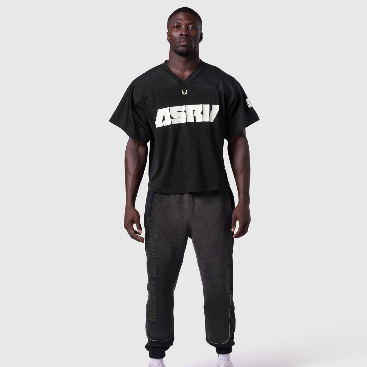 Ion-Mesh Crop Jersey in black with ASTRI text, worn by model with matching joggers, front view