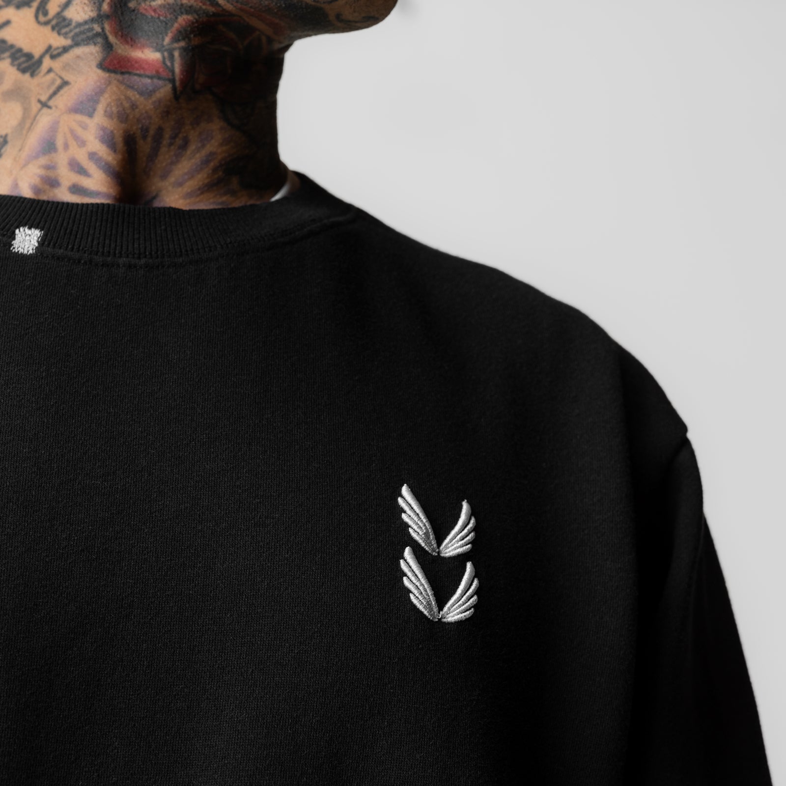 Tech Essential Distressed Crewneck in black, worn by model showing front logo detail and neck area