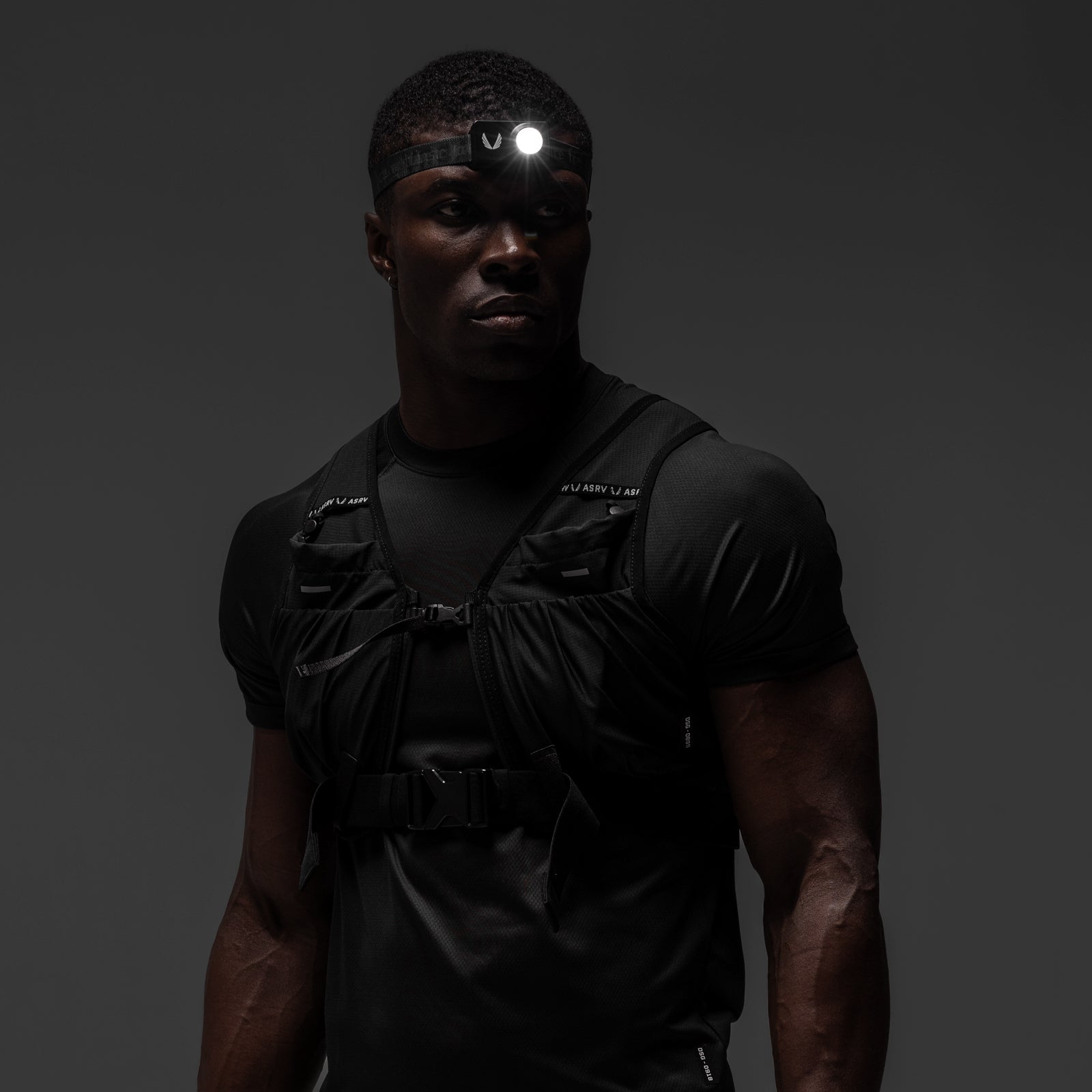 Black tactical vest worn with headlamp, front view on model