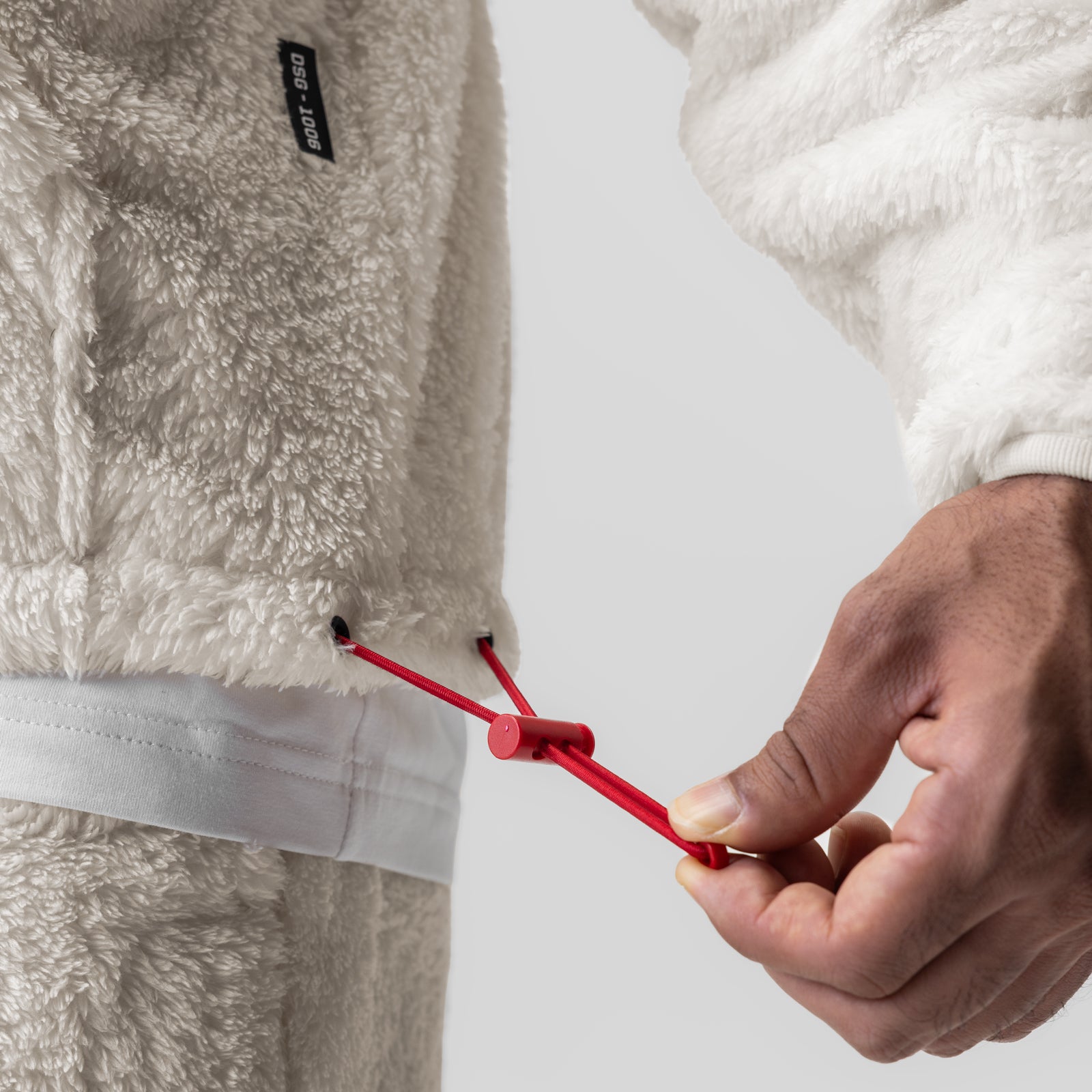 Sherpa Recovery 1/2 Zip in ivory cream being held, showing red drawstring detail