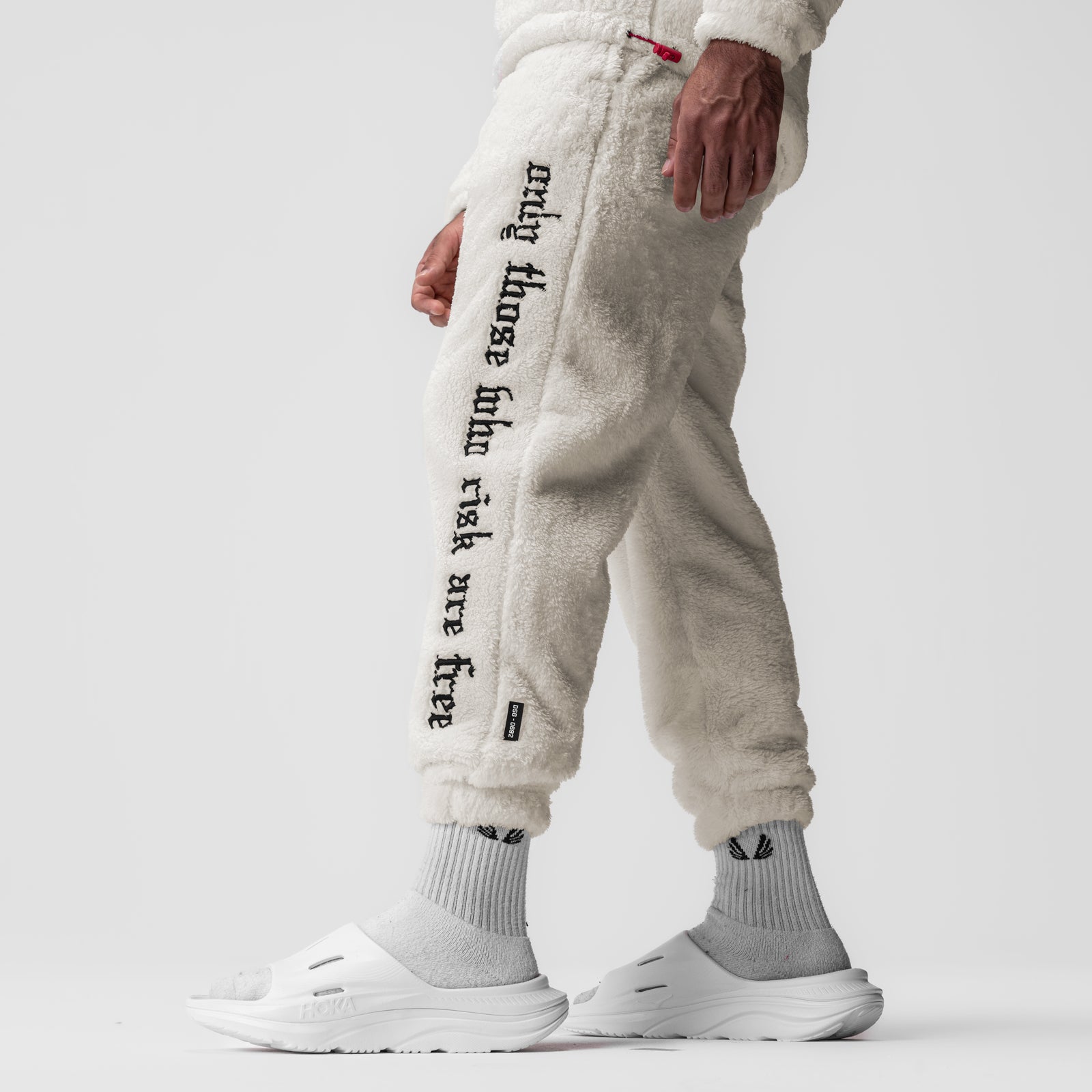 Sherpa Recovery Sweats in ivory cream worn by model, side view showing text down leg