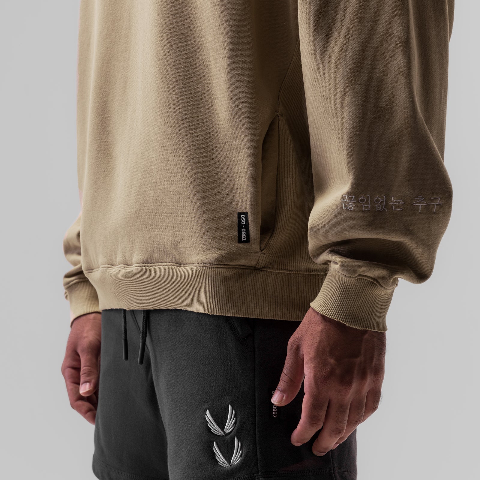 Tech Essential Distressed Crewneck in khaki worn with black joggers, detail view