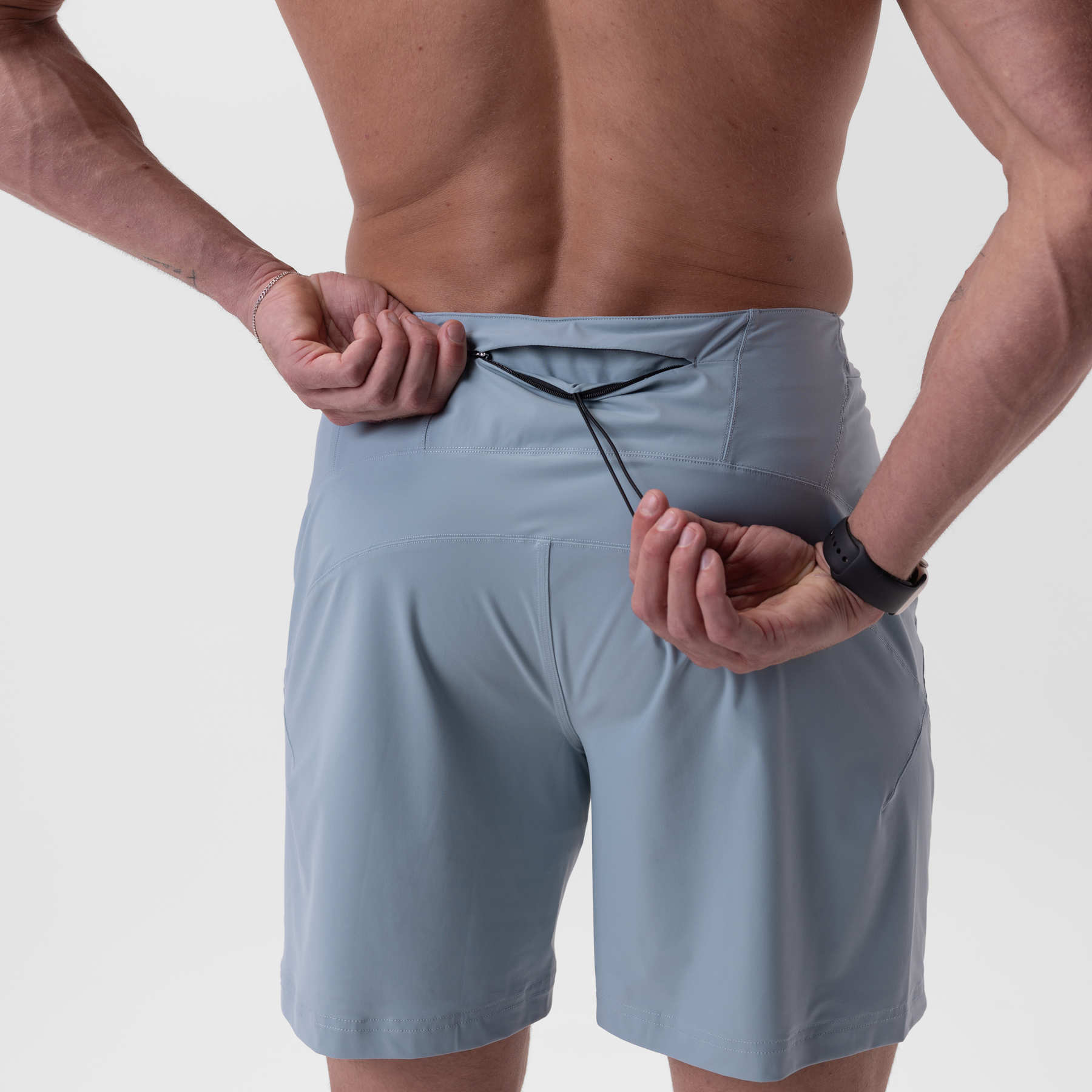 Revolutional® Board Short in Light Sky, worn by model, front view with hands adjusting waistband