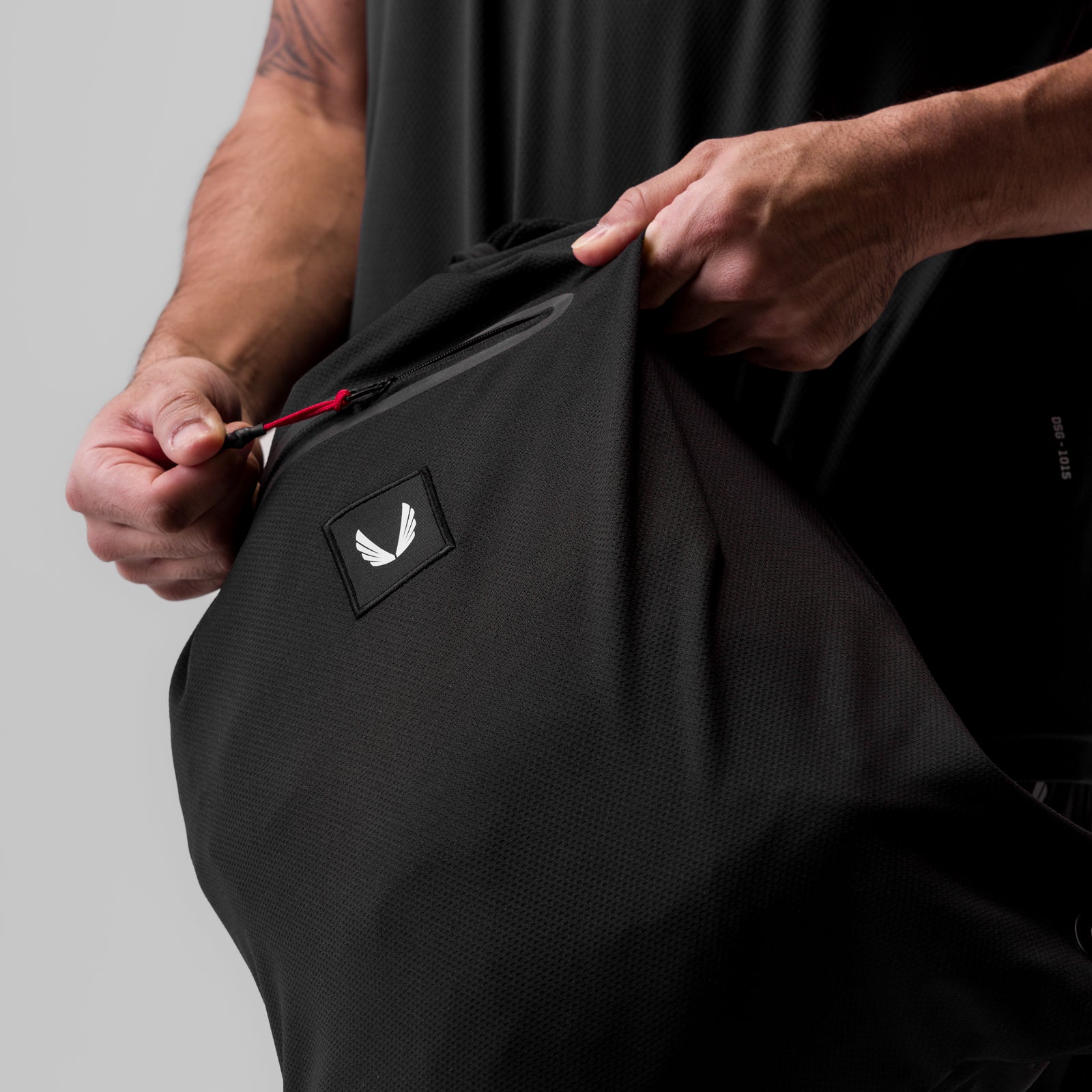 Antibacterial Mesh Drawstring Bag in black, held open by model to show interior red drawstring