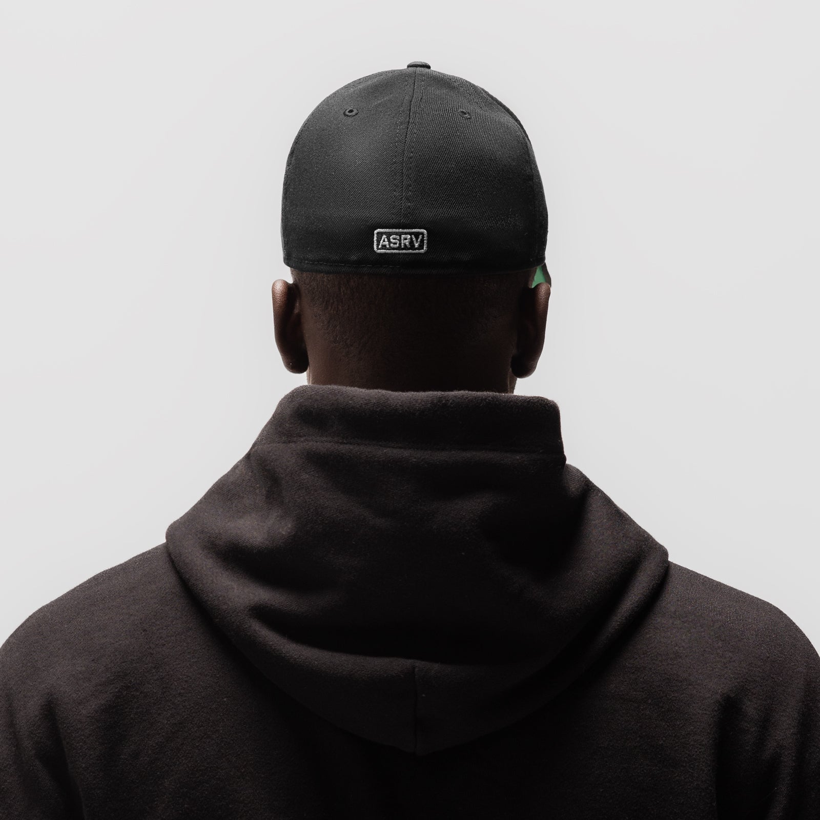 Black New Era 59Fifty Low Profile Hat worn by model from behind, showing back view
