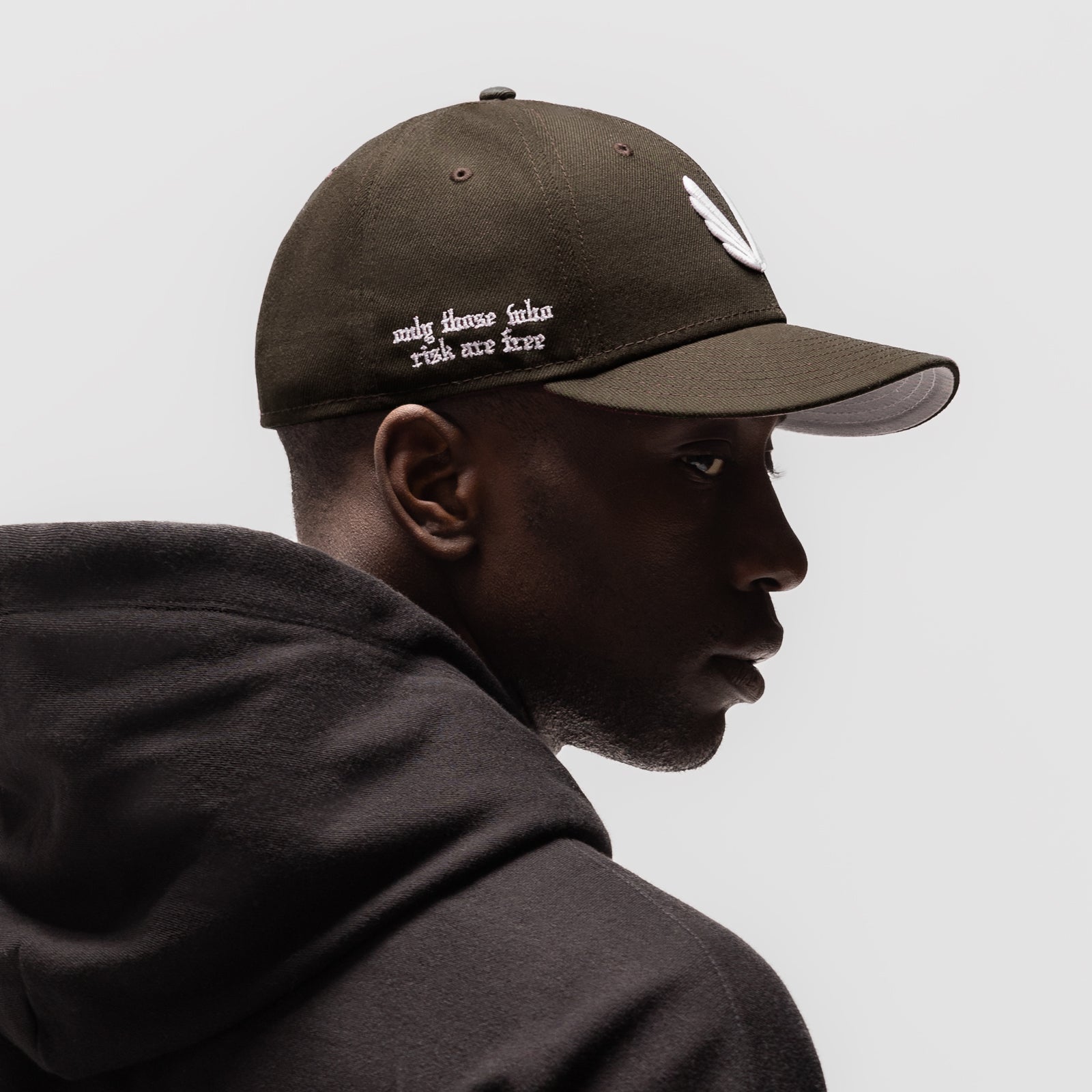 New Era 59Fifty Low Profile Hat in dark earth with white wings logo, worn by model in profile view