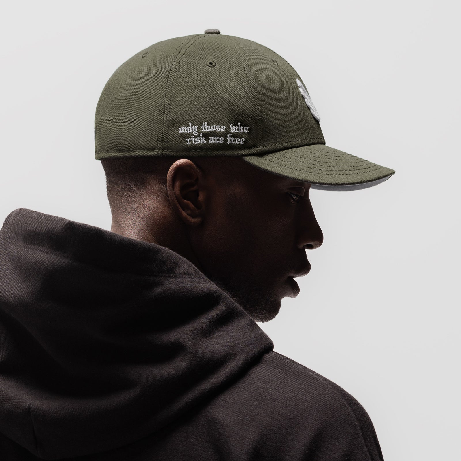 New Era 59Fifty Low Profile Hat in faded olive with white wings logo, worn by model in profile view