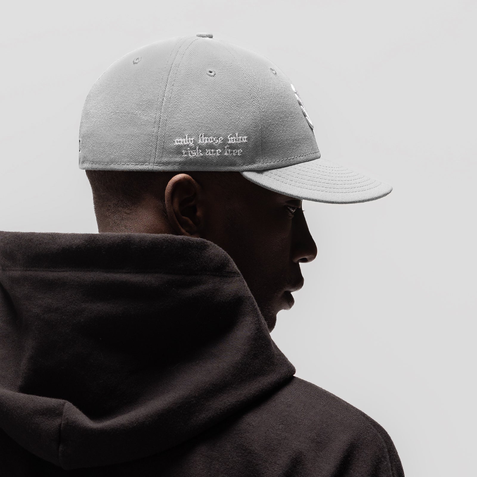 Grey New Era 59Fifty Low Profile Hat worn by model in profile view with black hoodie