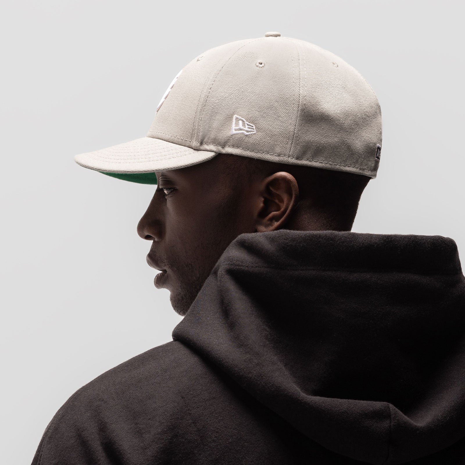 New Era 59Fifty Low Profile Hat in stone with white wings logo, worn by model in profile view