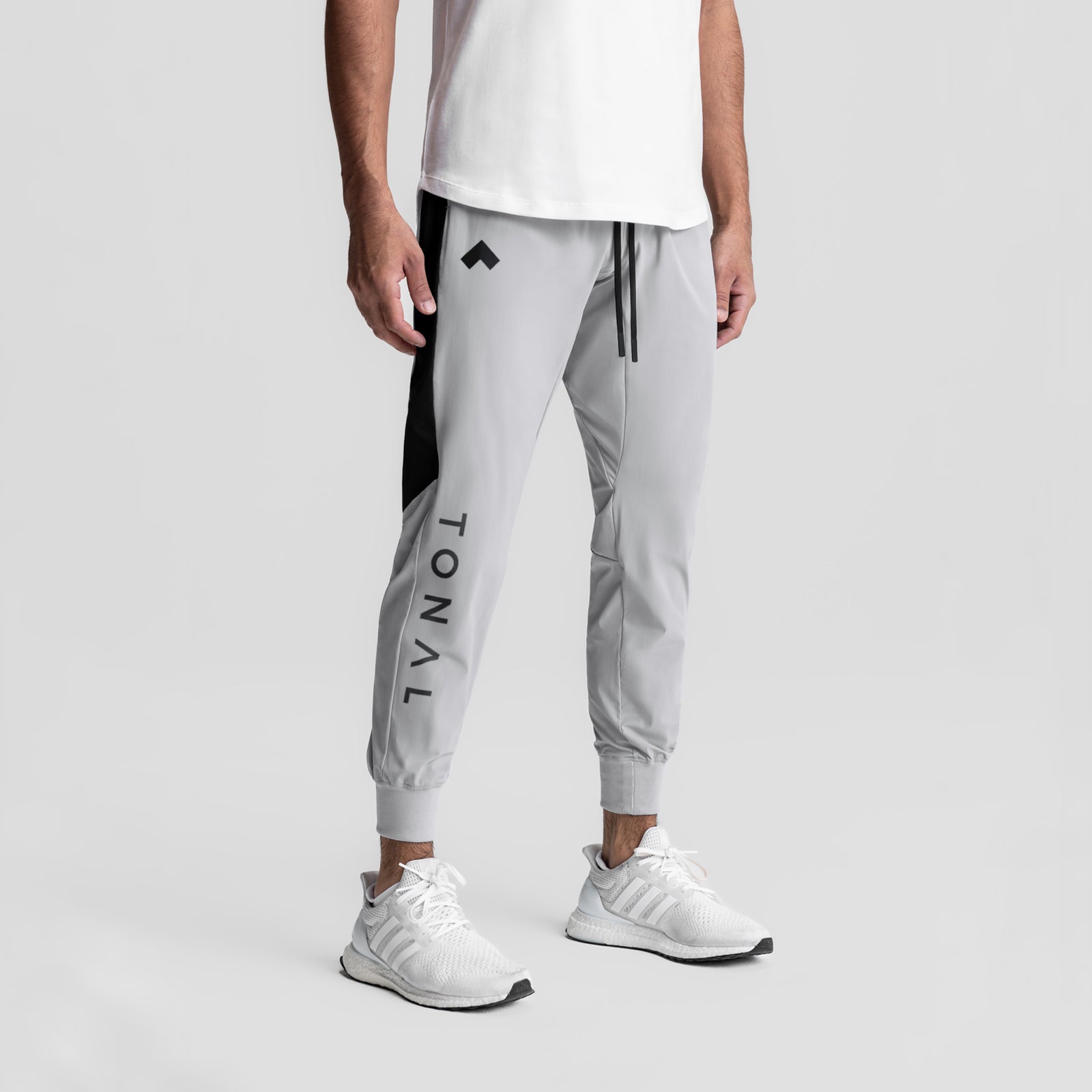 Slate grey cuffed training jogger with black side panels and LVNO branding, worn with white sneakers