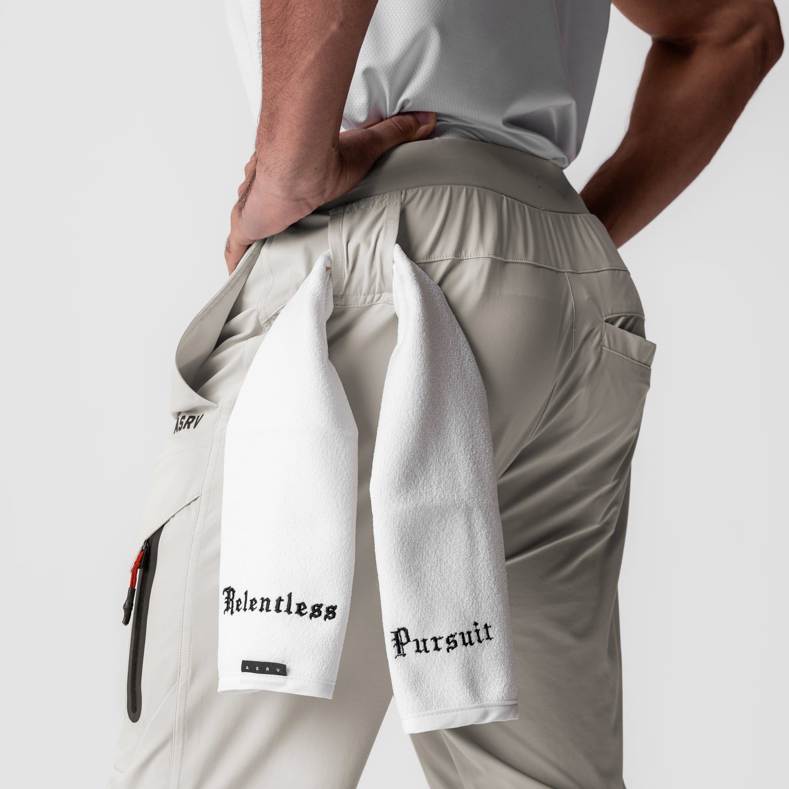 Tetra-Lite Tech High Rib Jogger in stone, worn by model holding white towel with 'Relentless Pursuit' text