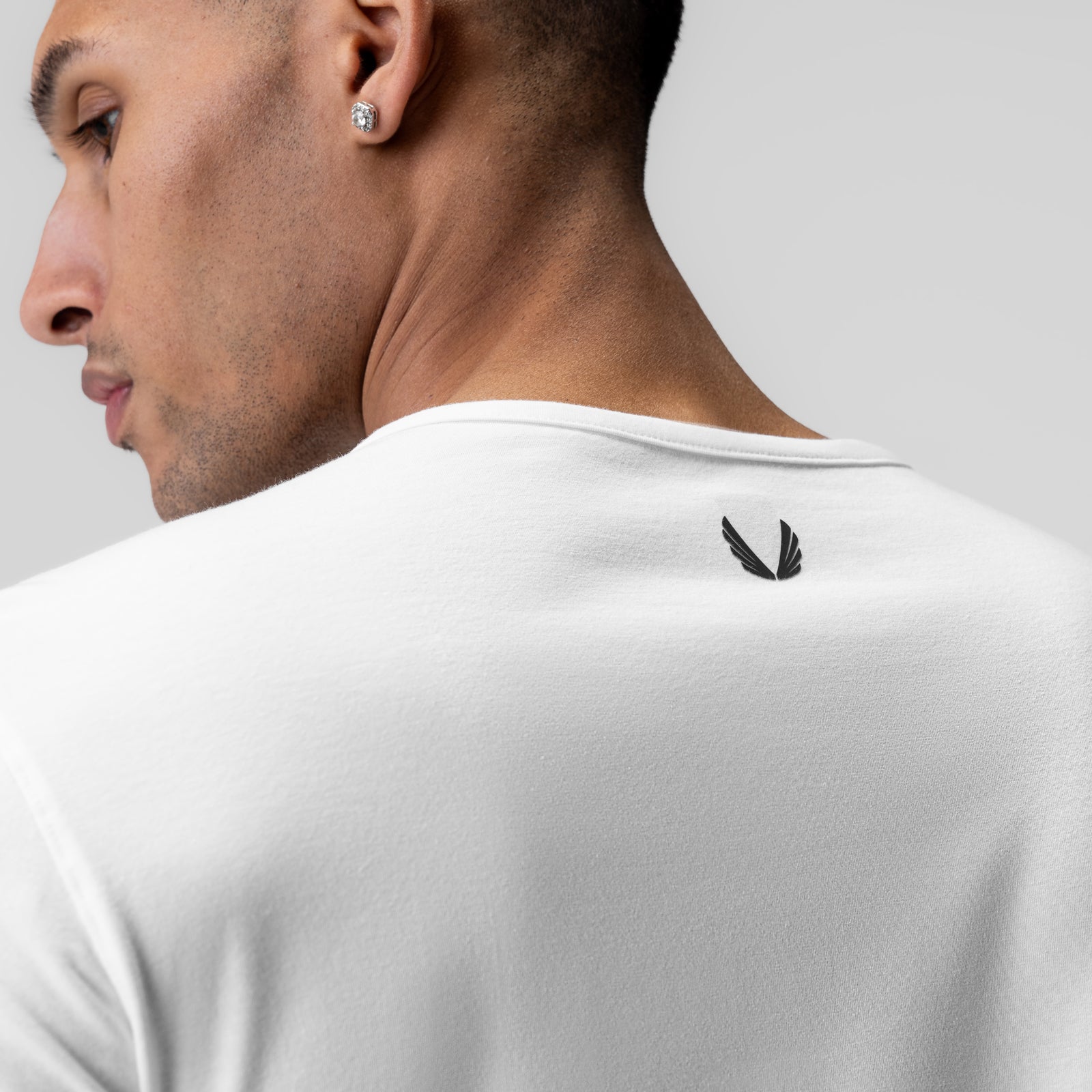 White long sleeve shirt on model, back view showing feather logo detail