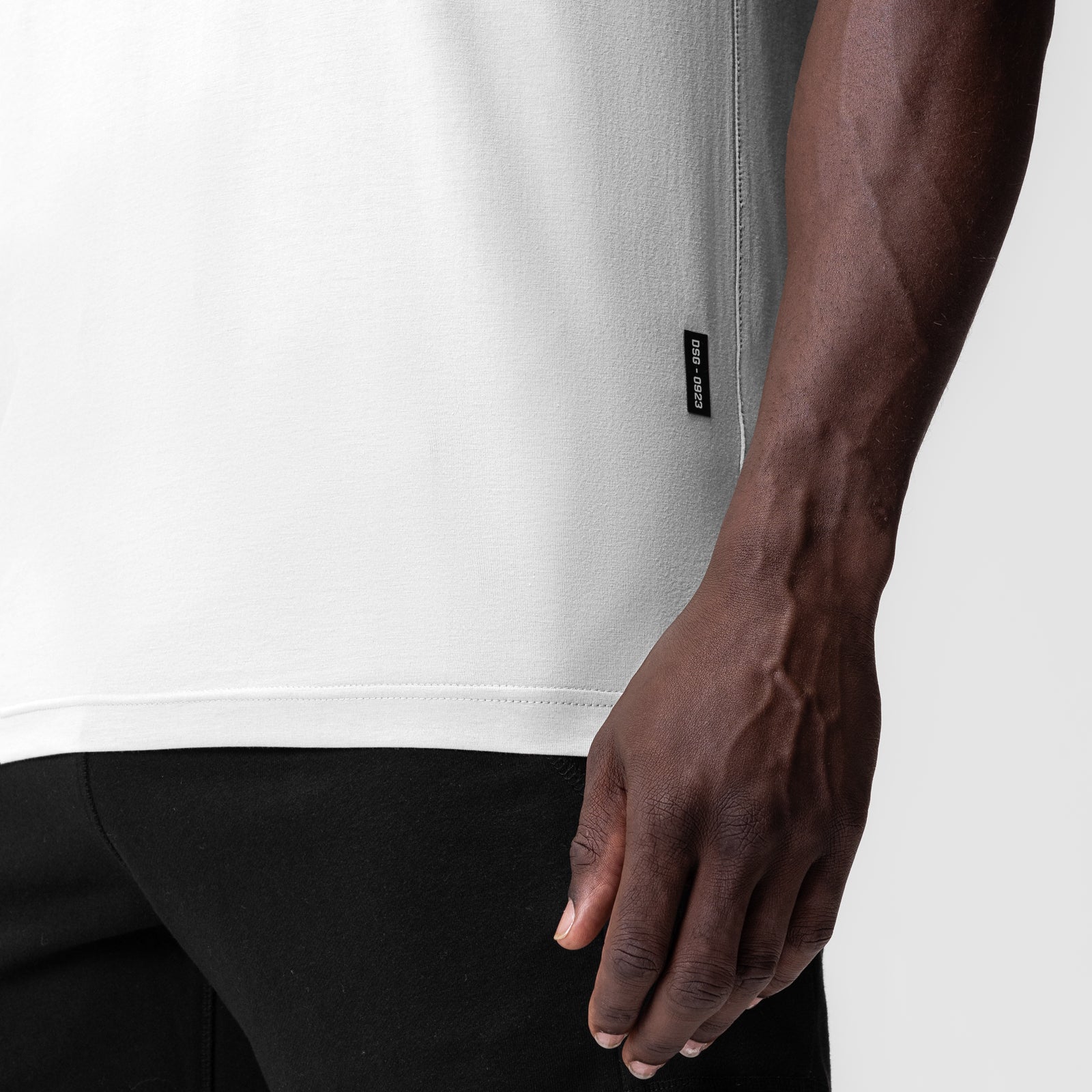 White Supima Essential Tee worn by model, side view with hand at waist