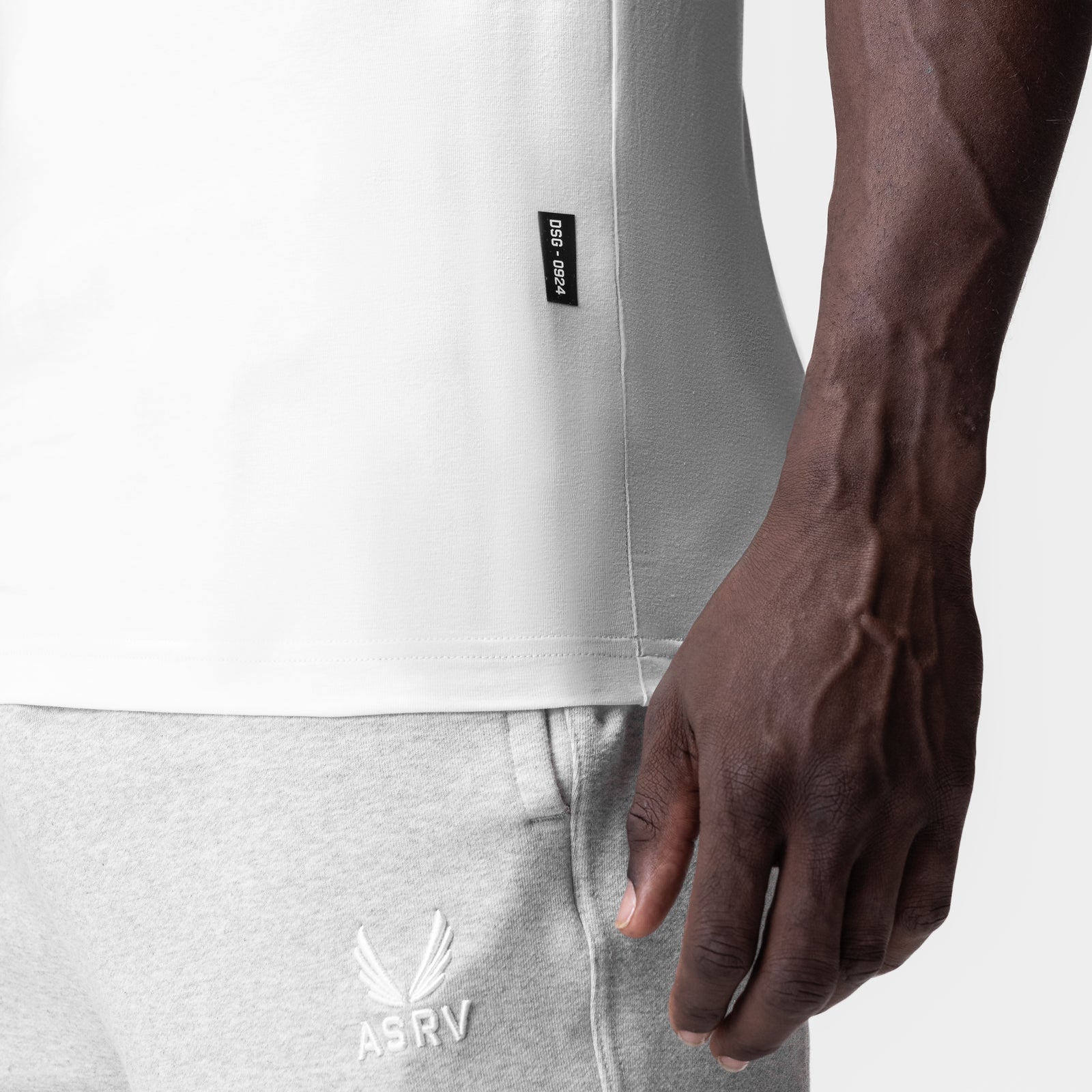 Supima Essential Slim Tank in white, worn by model showing side detail and ASRV logo