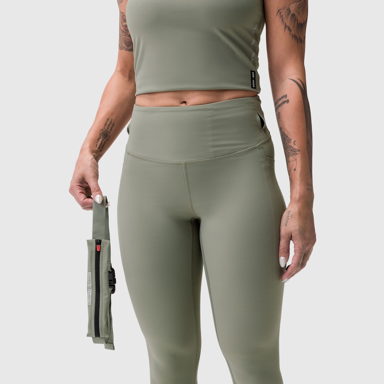 W030 Lycra 3-in-1 Legging in sage worn by model holding detachable pouch, front view