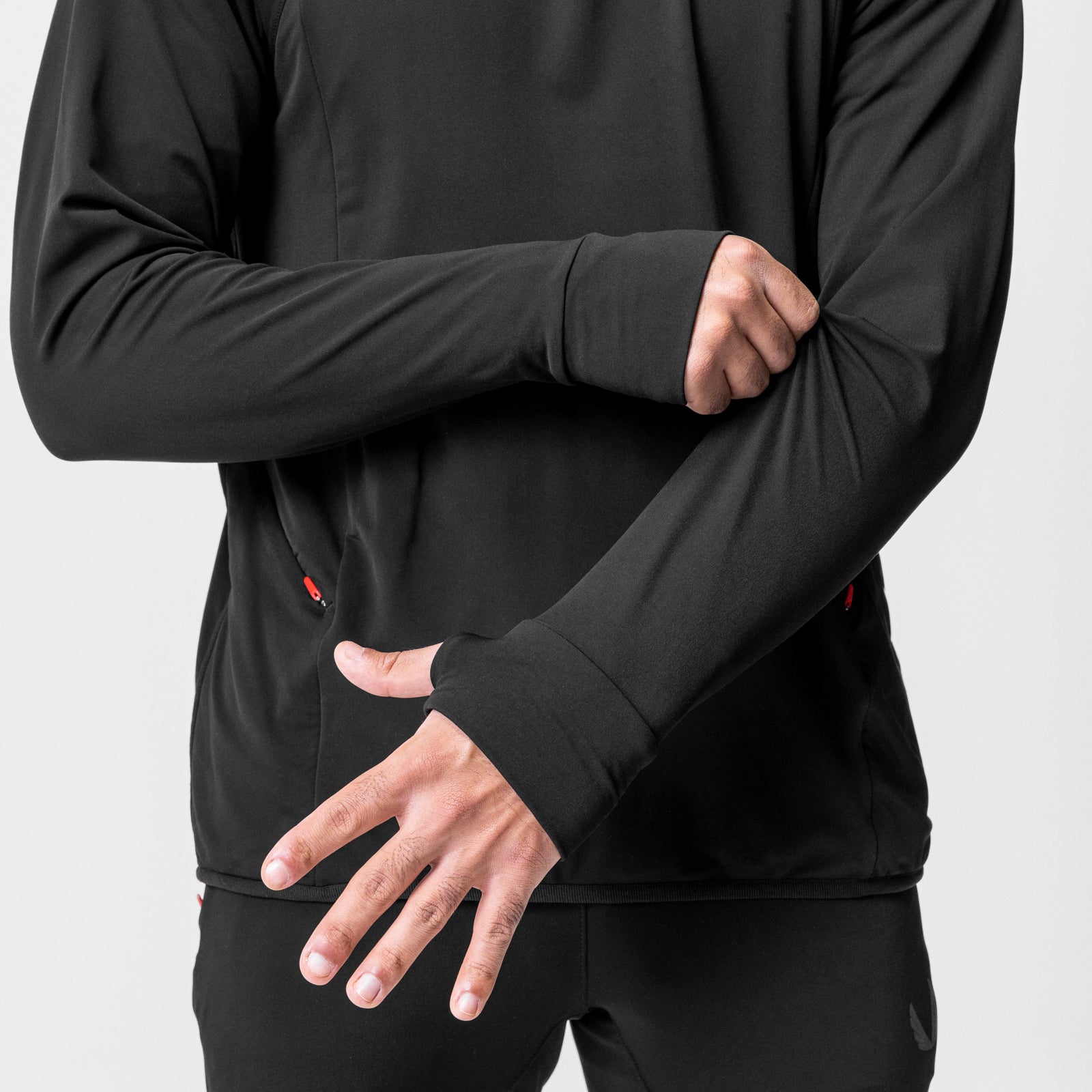 Black training hoodie worn by model with arms crossed, front view