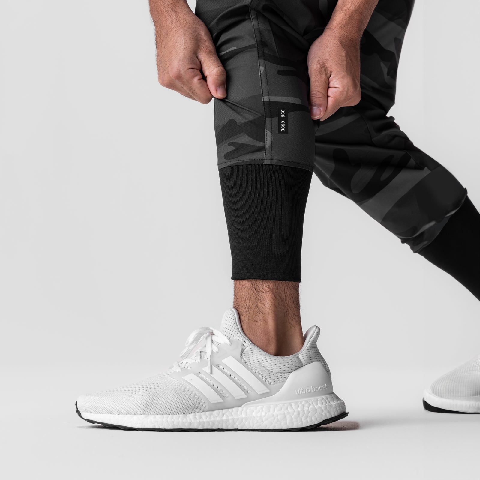 Black camo tech jogger worn by model with white sneakers, side view