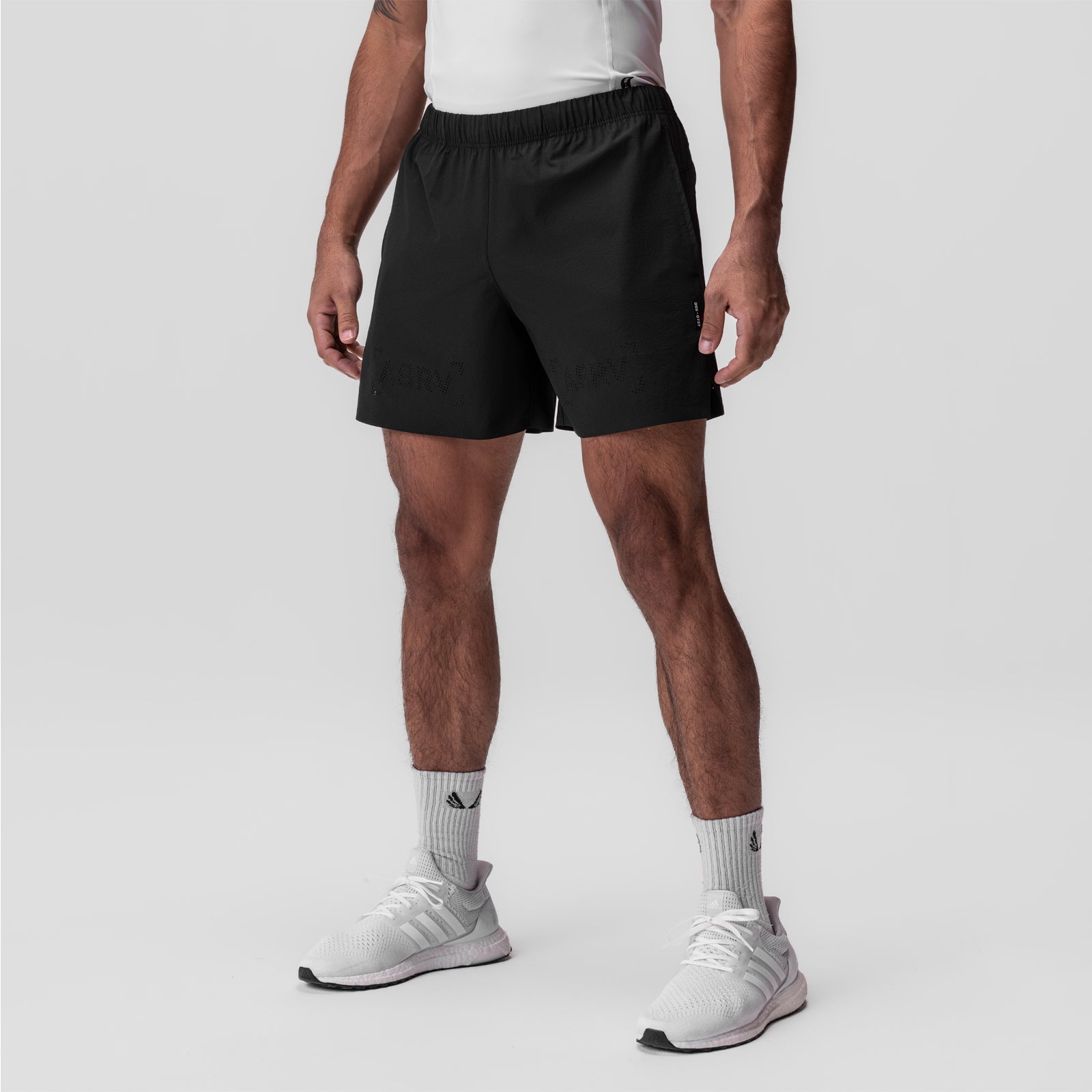 Black ripstop 6" perforated shorts on model with white sneakers and socks, front view