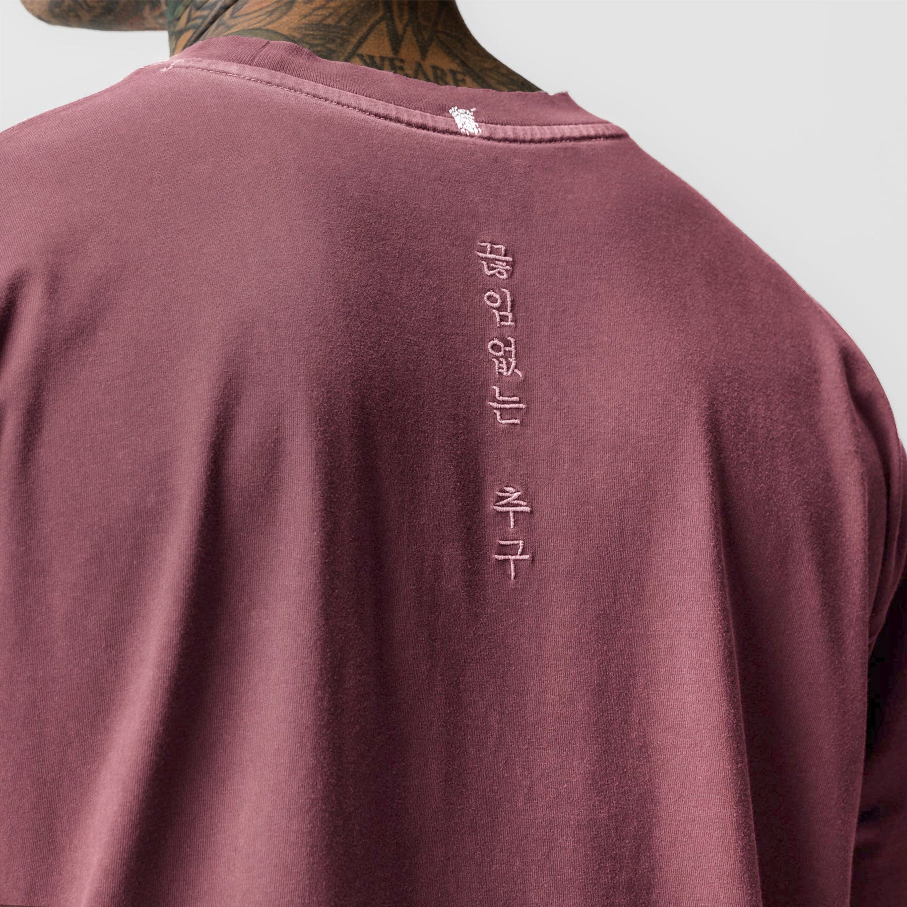 Tech Essential Relaxed Tee in Faded Crimson worn by model, back view showing vertical text graphic