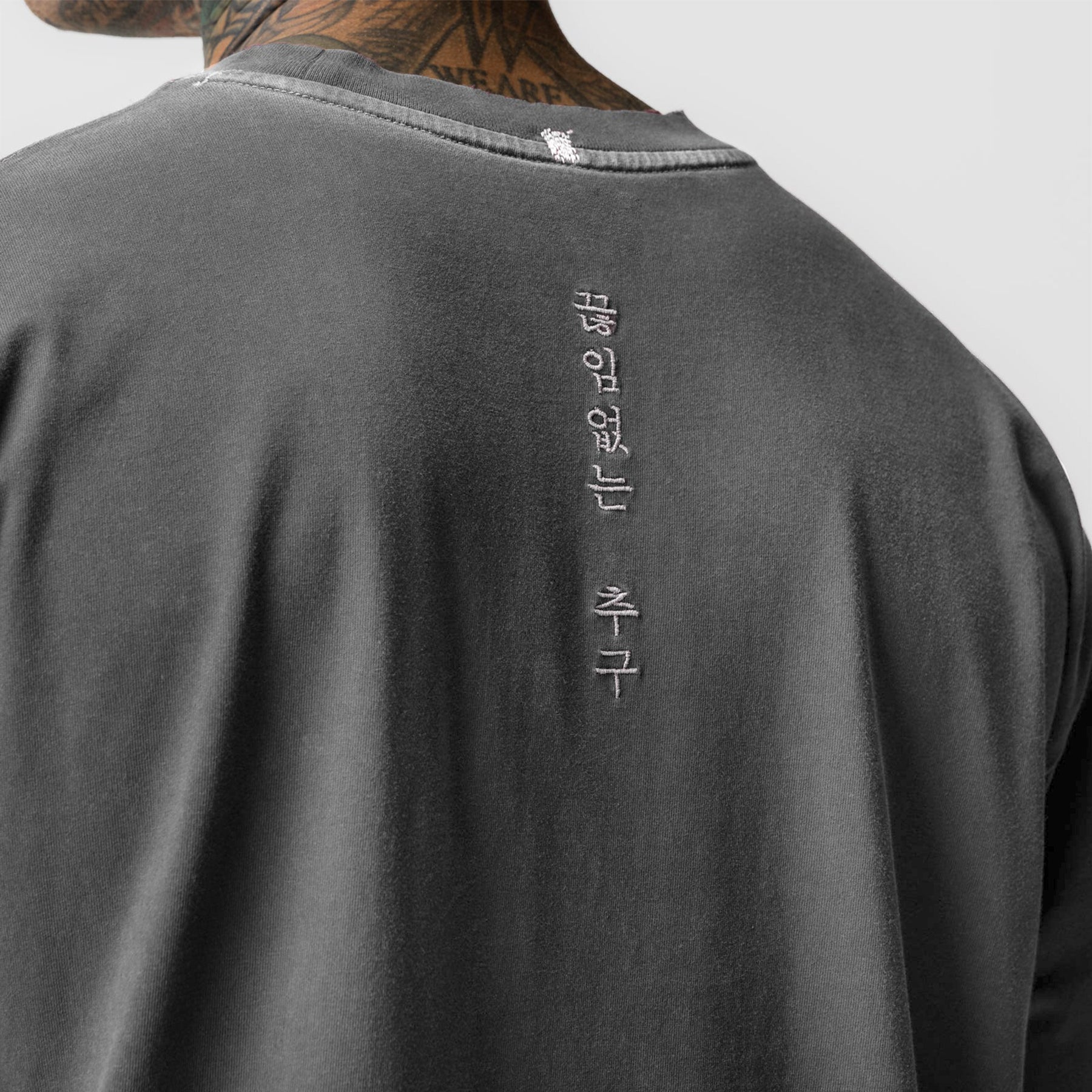 Tech Essential Relaxed Tee in faded grey worn by model, back view with vertical text detail