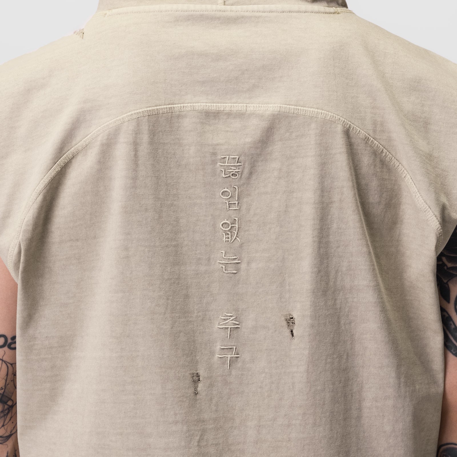 Tech Essential Cutoff Hoodie in faded beige, back view on model with visible distressing