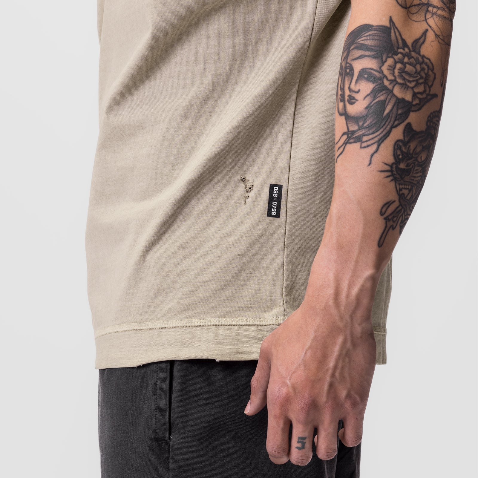Tech Essential Cutoff Hoodie in faded beige worn by model with visible arm tattoos, side view