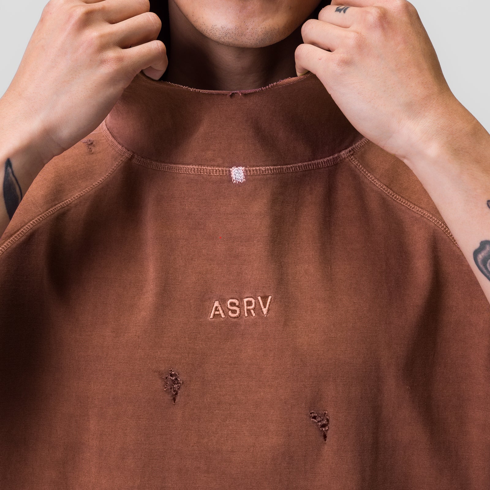 ASRV Tech Essential Cutoff Hoodie in faded rust, worn by model pulling at neckline