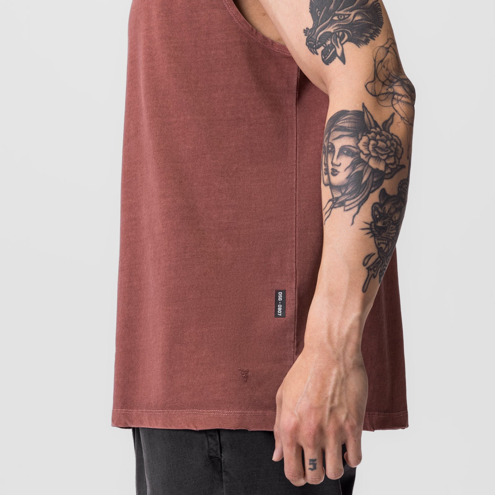 Tech Essential Relaxed Cutoff tank top in faded brick, worn by model showing side view