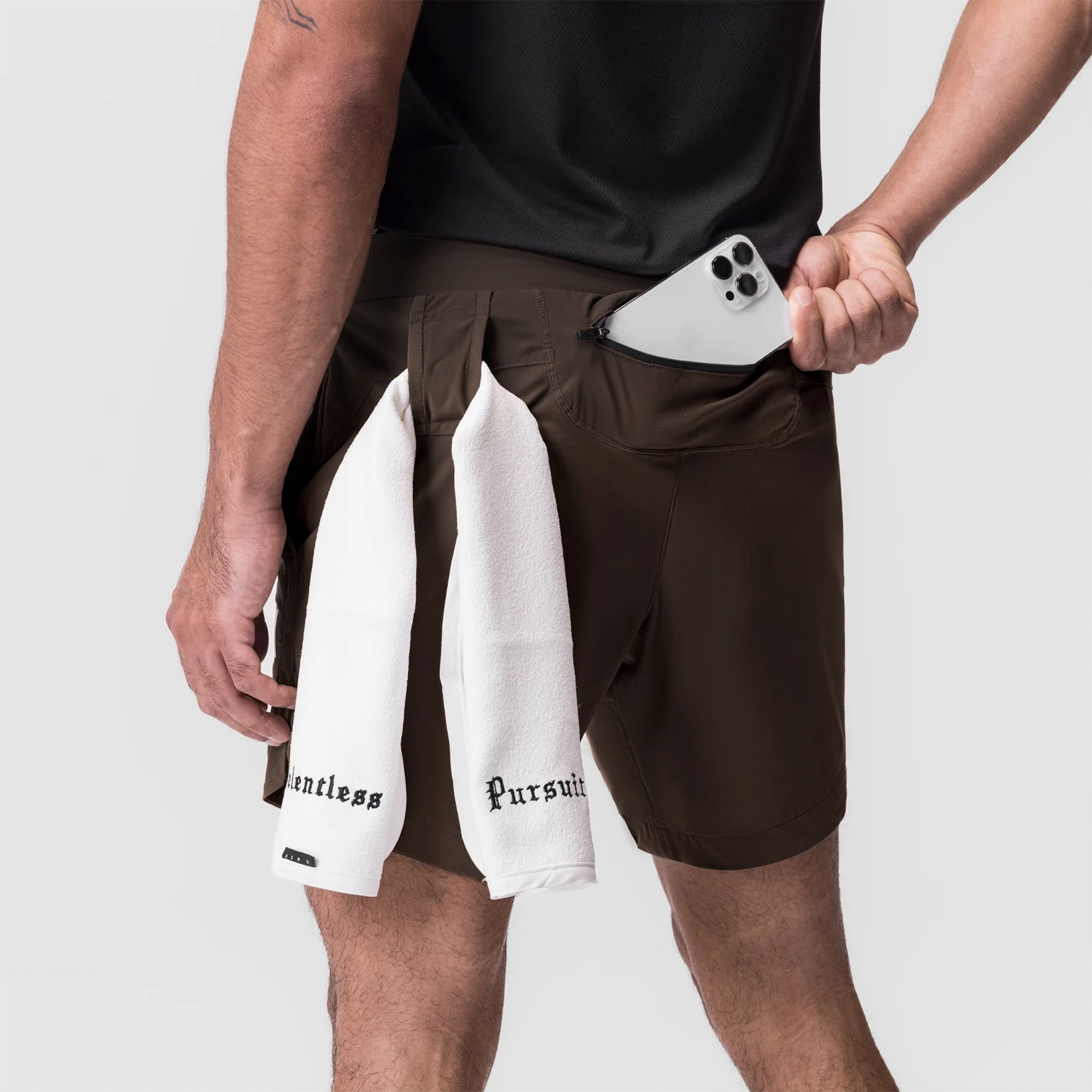 Tetra-Lite 7" Linerless Short in Dark Earth, worn with white towel and smartphone in pocket