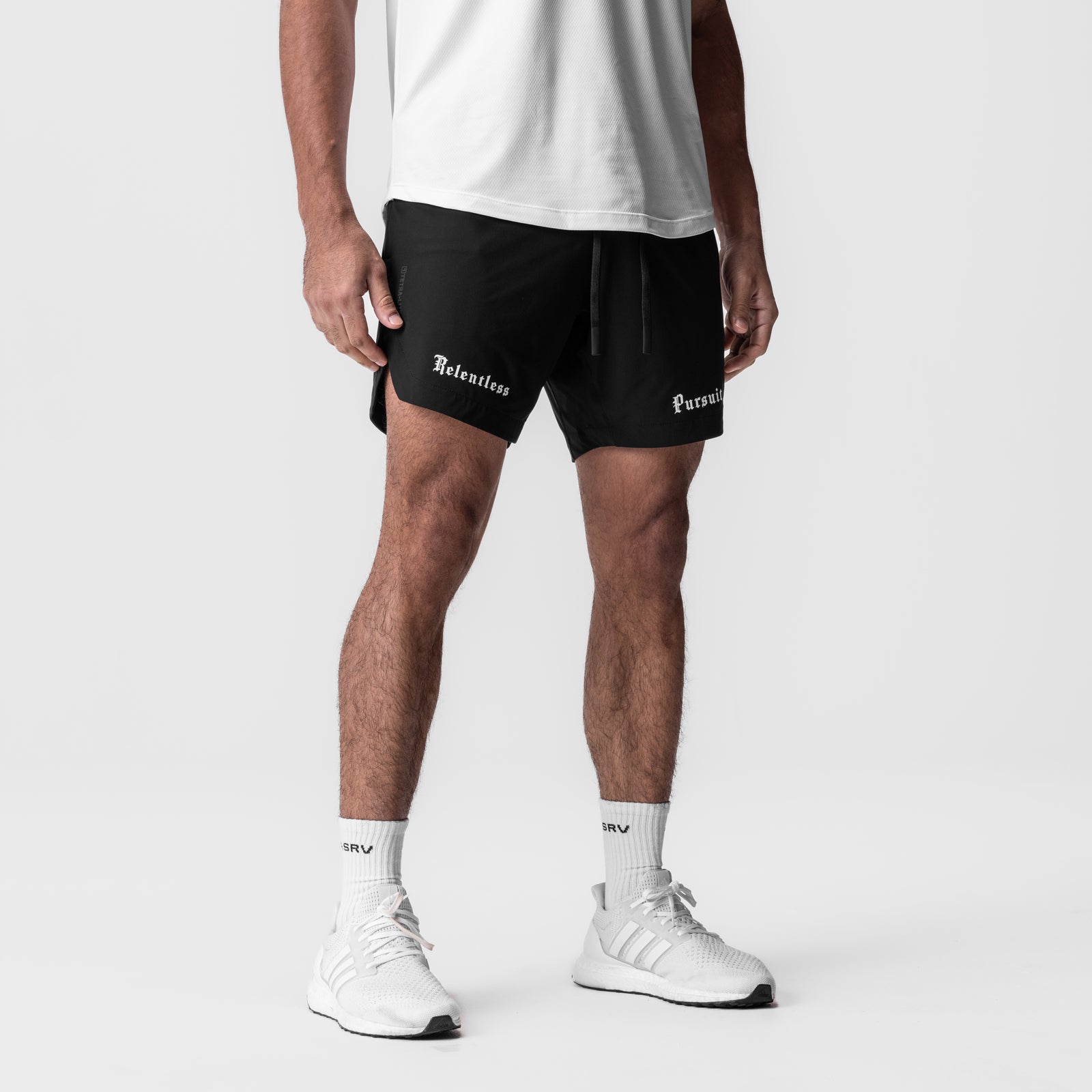 Tetra-Lite 7" Linerless Short in black with 'Relentless Pursuit' text, worn by model with white sneakers