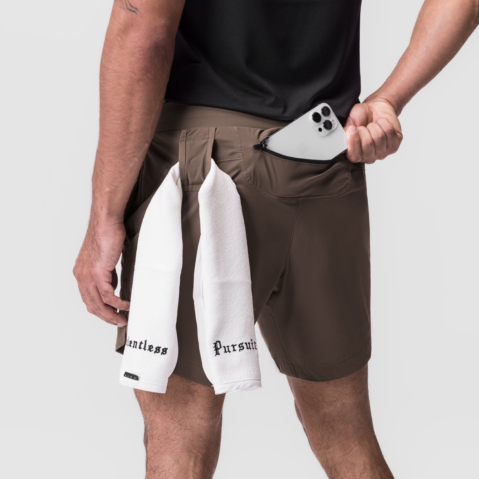 Tetra-Lite 7" Linerless Short in Deep Taupe, worn with white towel, holding phone