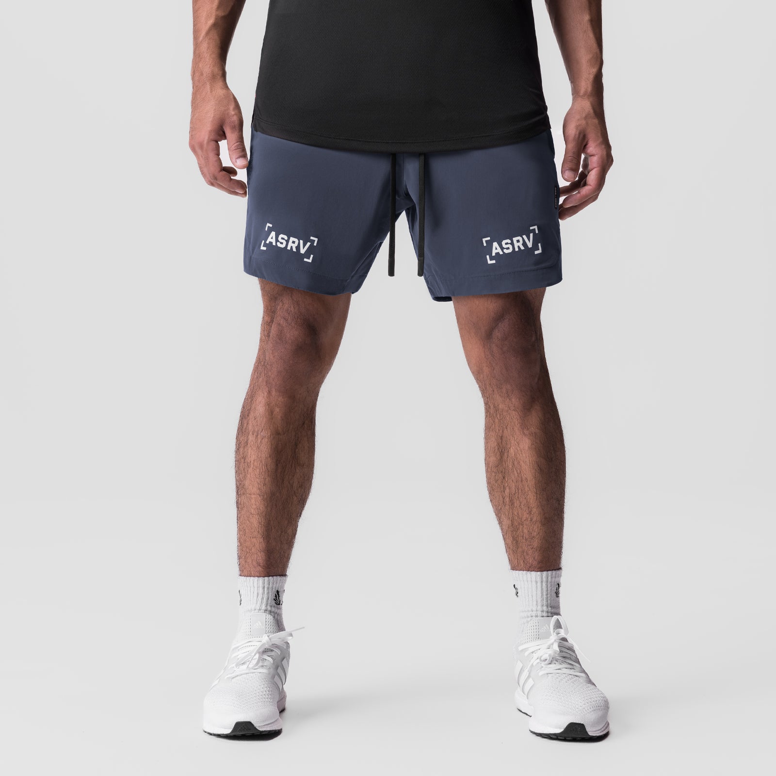 Navy Tetra-Lite 7" linerless shorts with bracket logo, worn by model with white sneakers